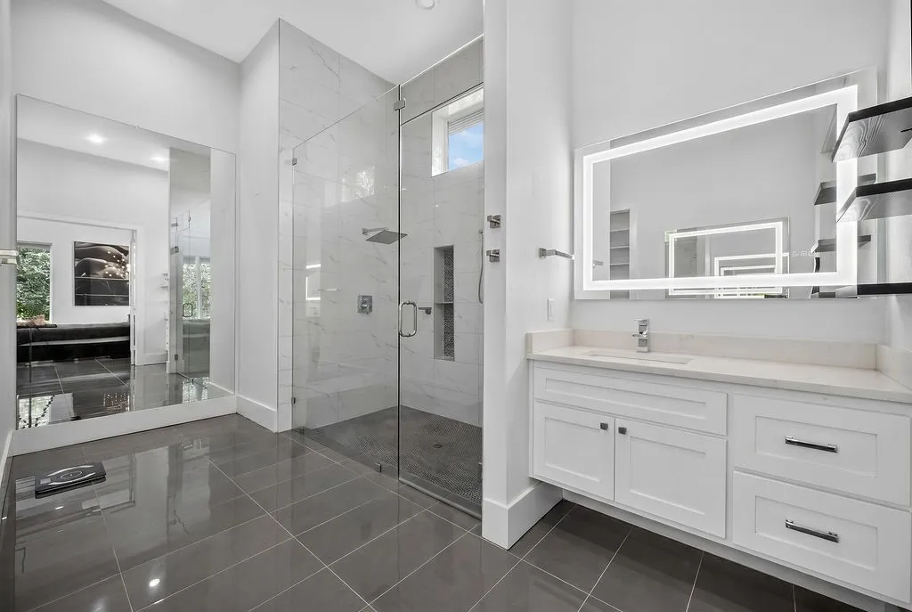 Modern bathroom featuring a spacious glass-enclosed shower with tile surround and rain showerhead