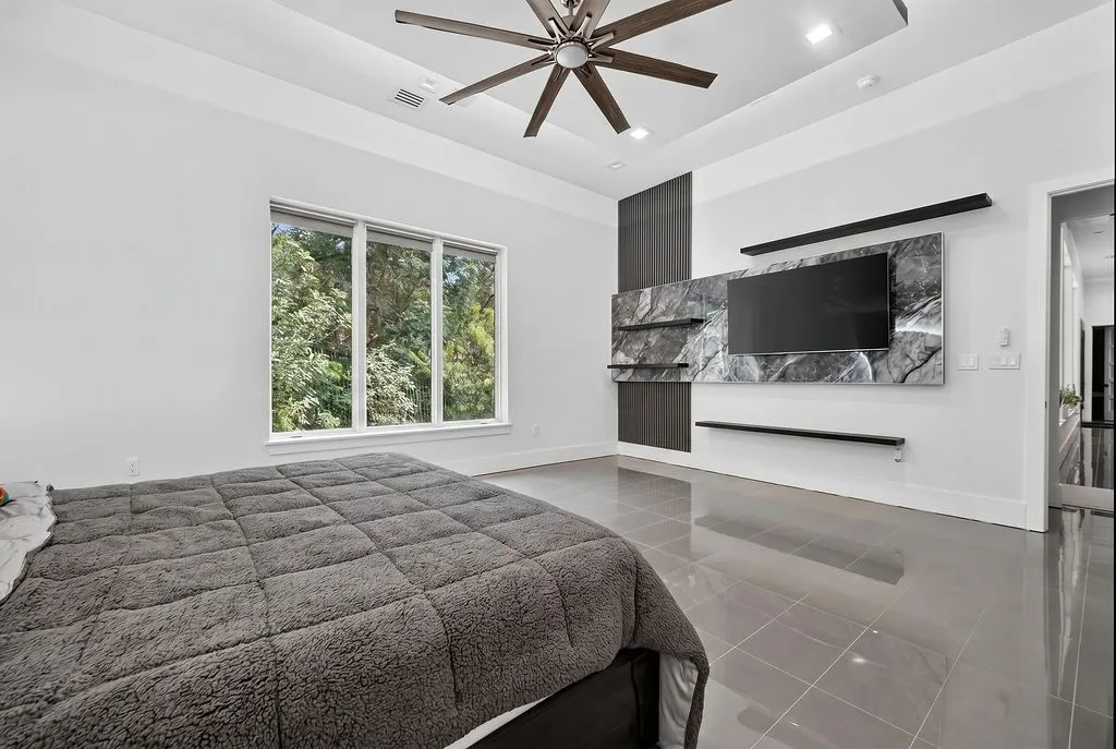 Spacious room featuring a tray ceiling with recessed lighting and a ceiling fan