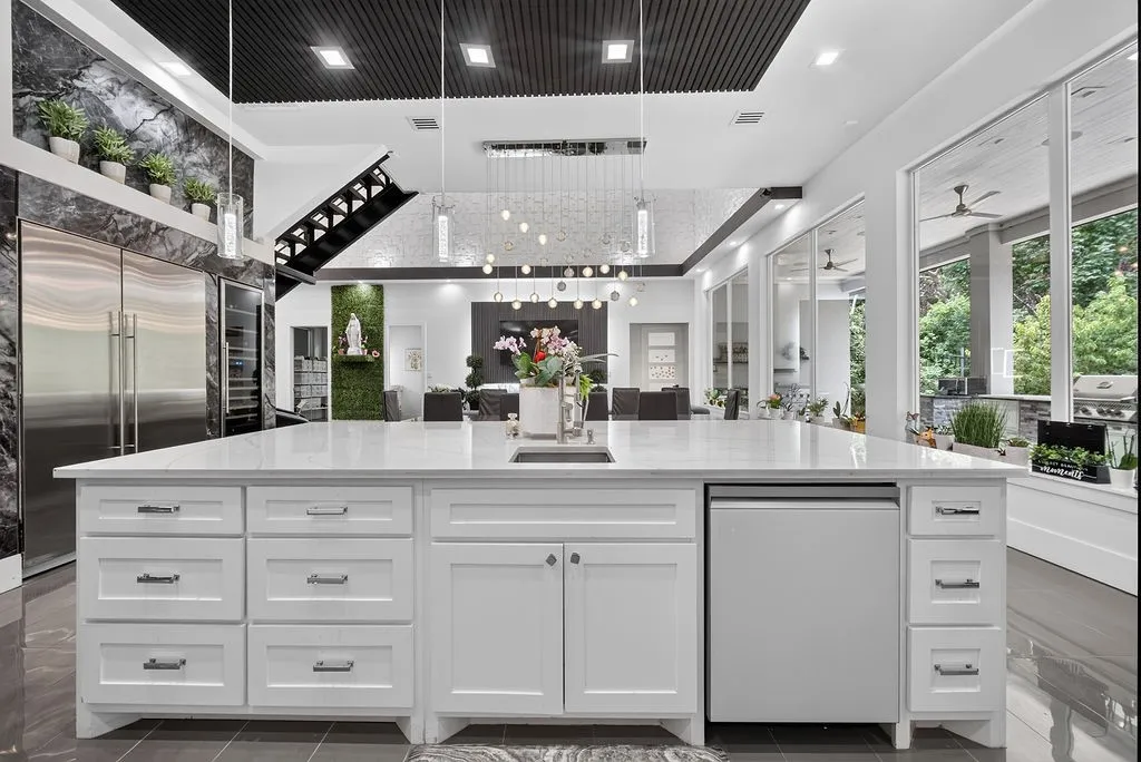 Spacious kitchen featuring a large white island with integrated sink, white cabinetry, and a built-in dishwasher