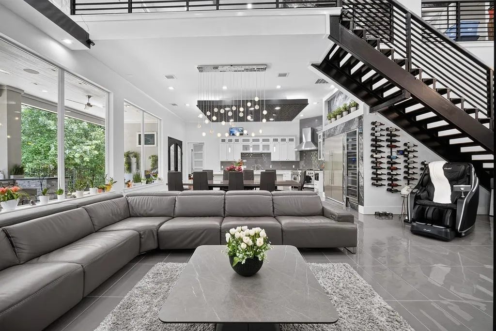 Open-concept living area featuring large format tile flooring, a modern floating staircase with metal railings, a built-in wine storage wall, and a gourmet kitchen with stainless steel appliances