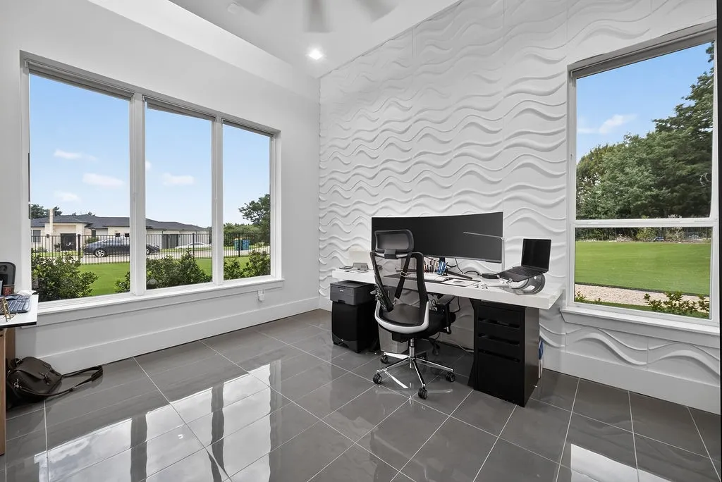 Room featuring a textured accent wall, sleek grey tile flooring, and a contemporary ceiling fan