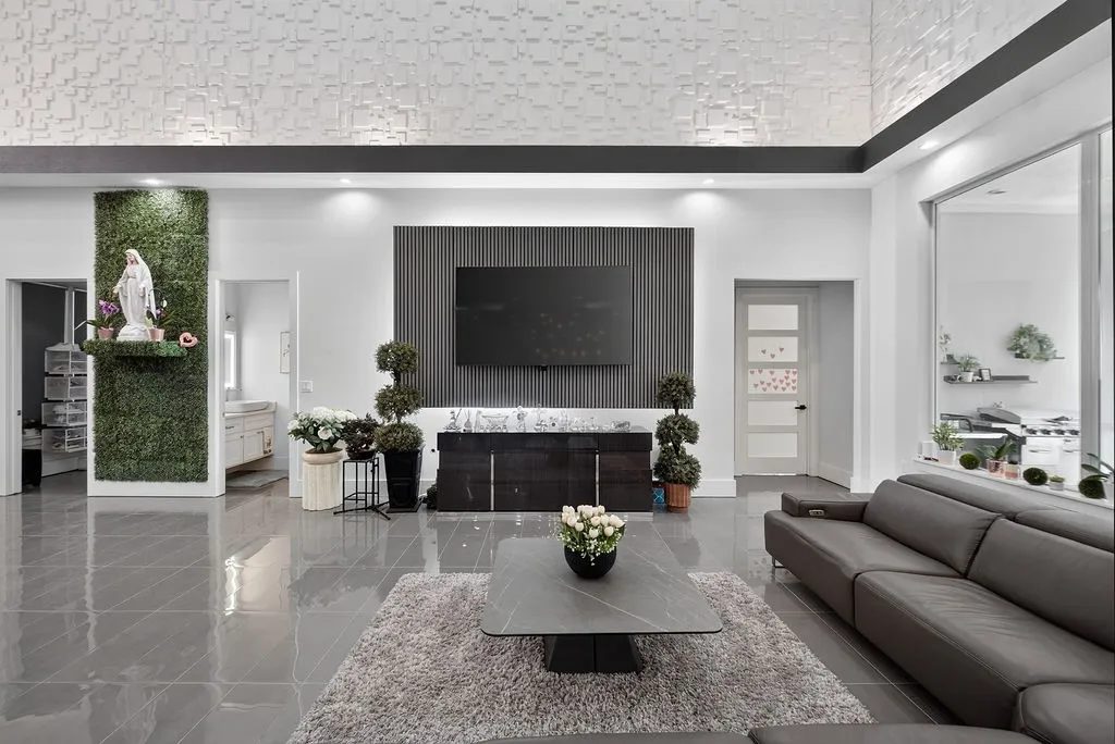 Spacious living area featuring polished tile flooring, a textured accent wall, recessed lighting, a built-in media console, and a large window