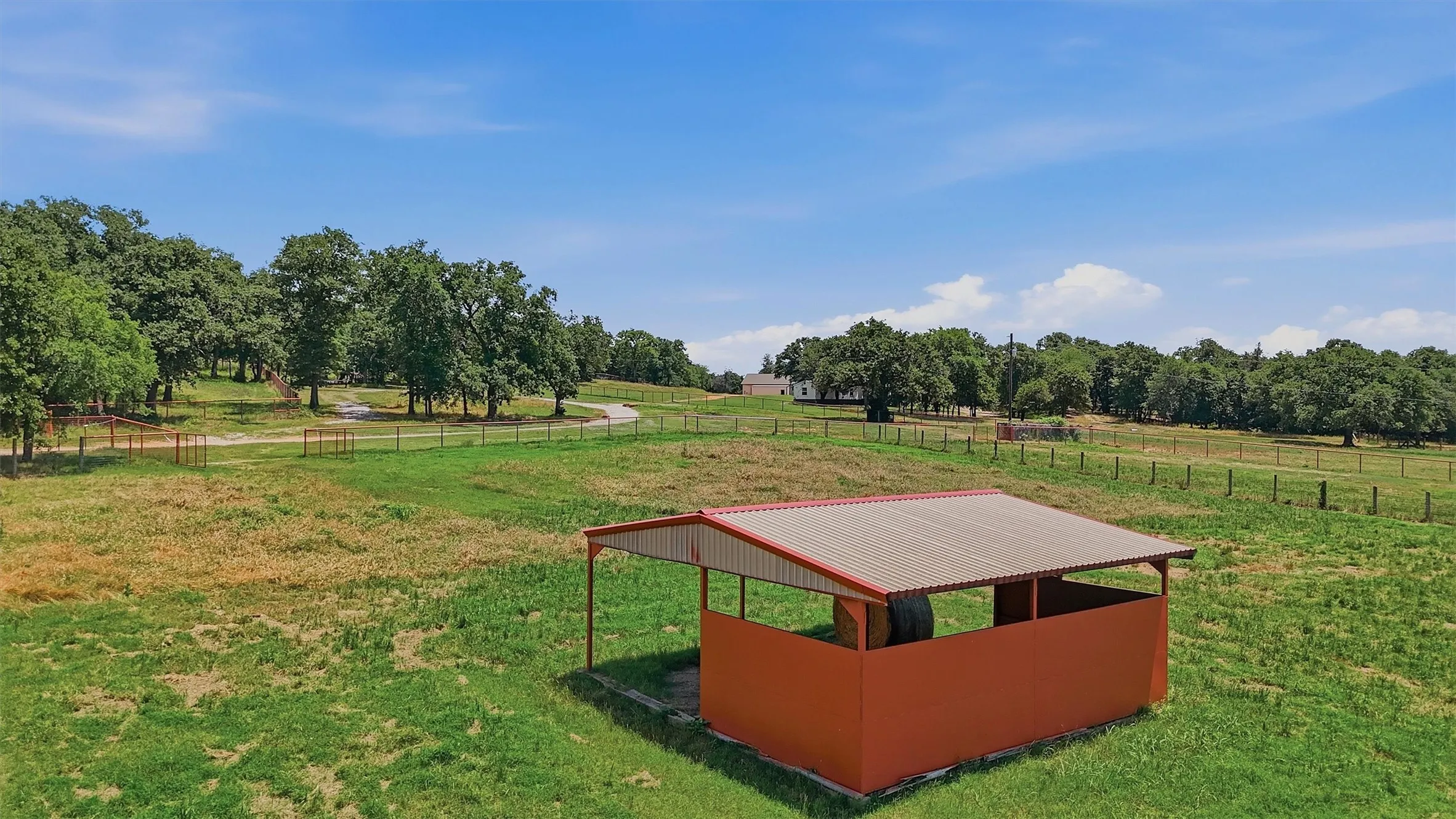 Open-air shelter with a sloped metal roof and enclosed orange siding