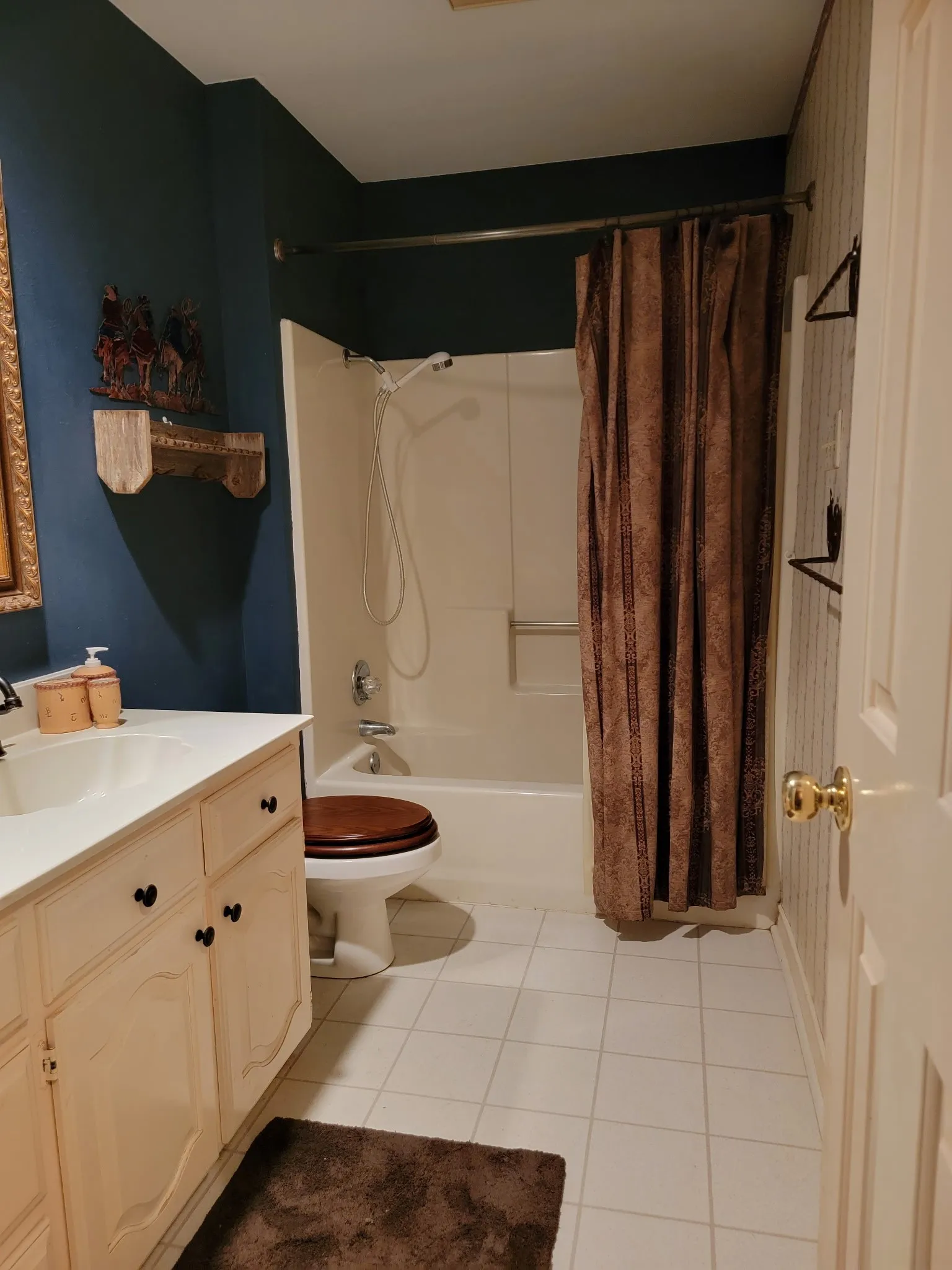 Full bathroom featuring a white vanity with integrated sink, a built-in bathtub with shower, white tile flooring, and a wall-mounted medicine cabinet