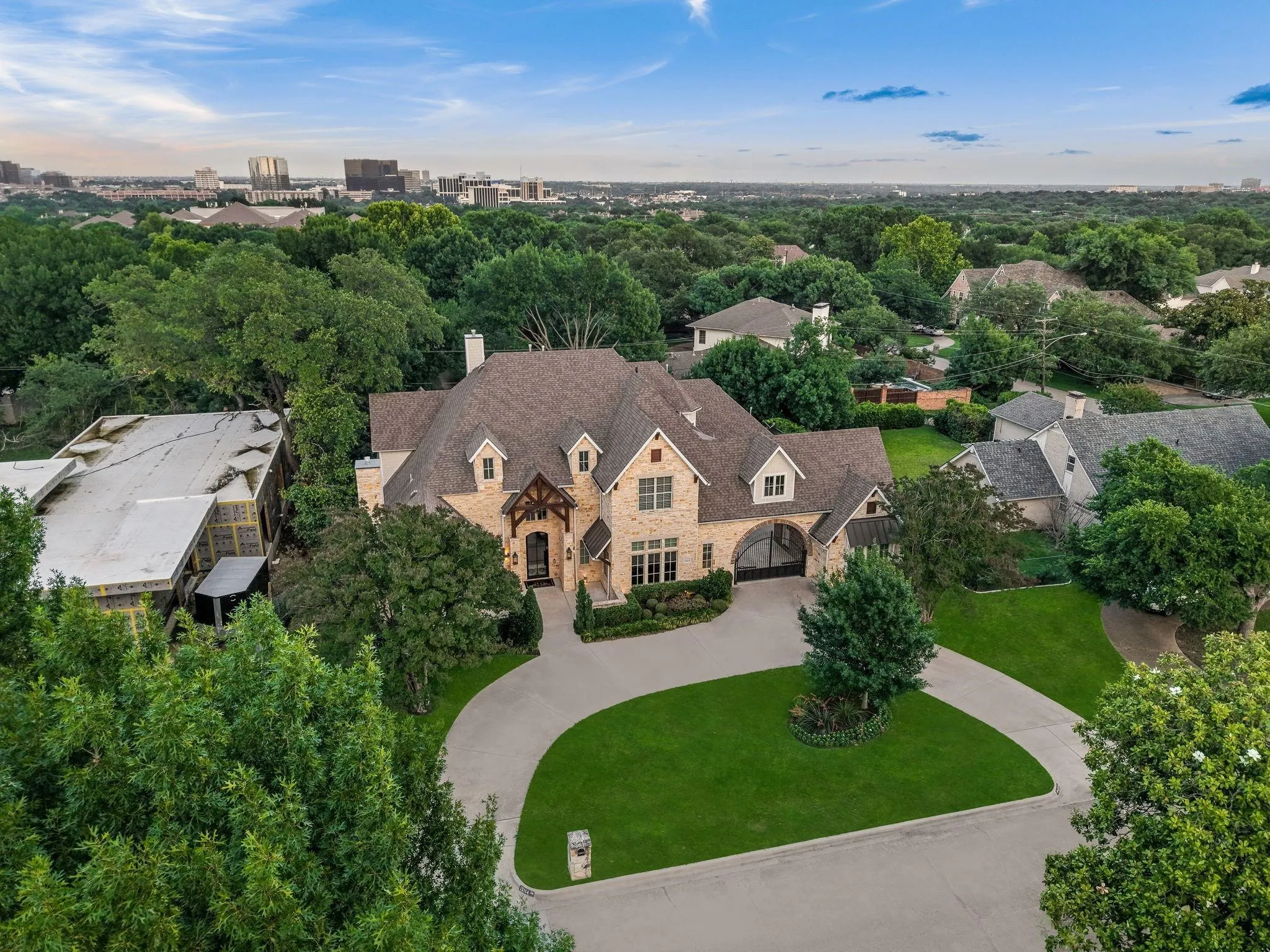 Stone and brick facade residence featuring a multi-gabled roof, covered arched entryway, and mature landscaping