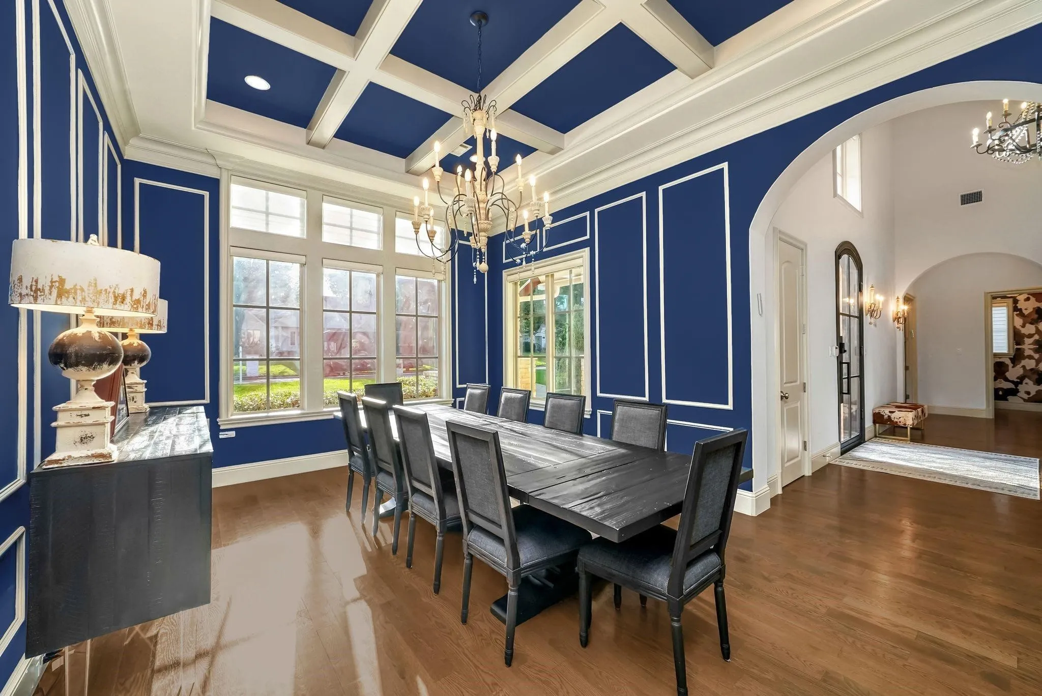 Formal dining space featuring hardwood flooring, a coffered ceiling, extensive wall molding, and multiple large pane windows