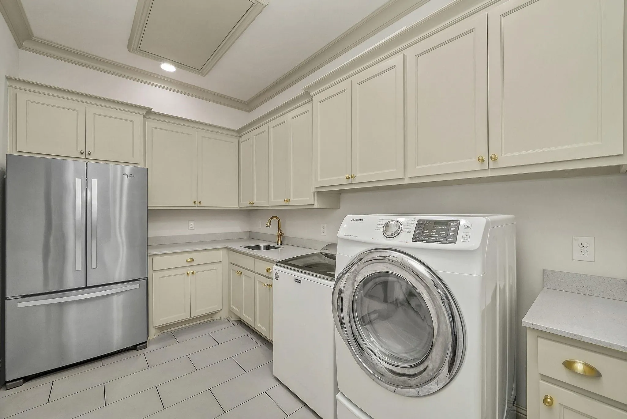 Utility room featuring extensive cabinetry, light-toned countertops, and tile flooring