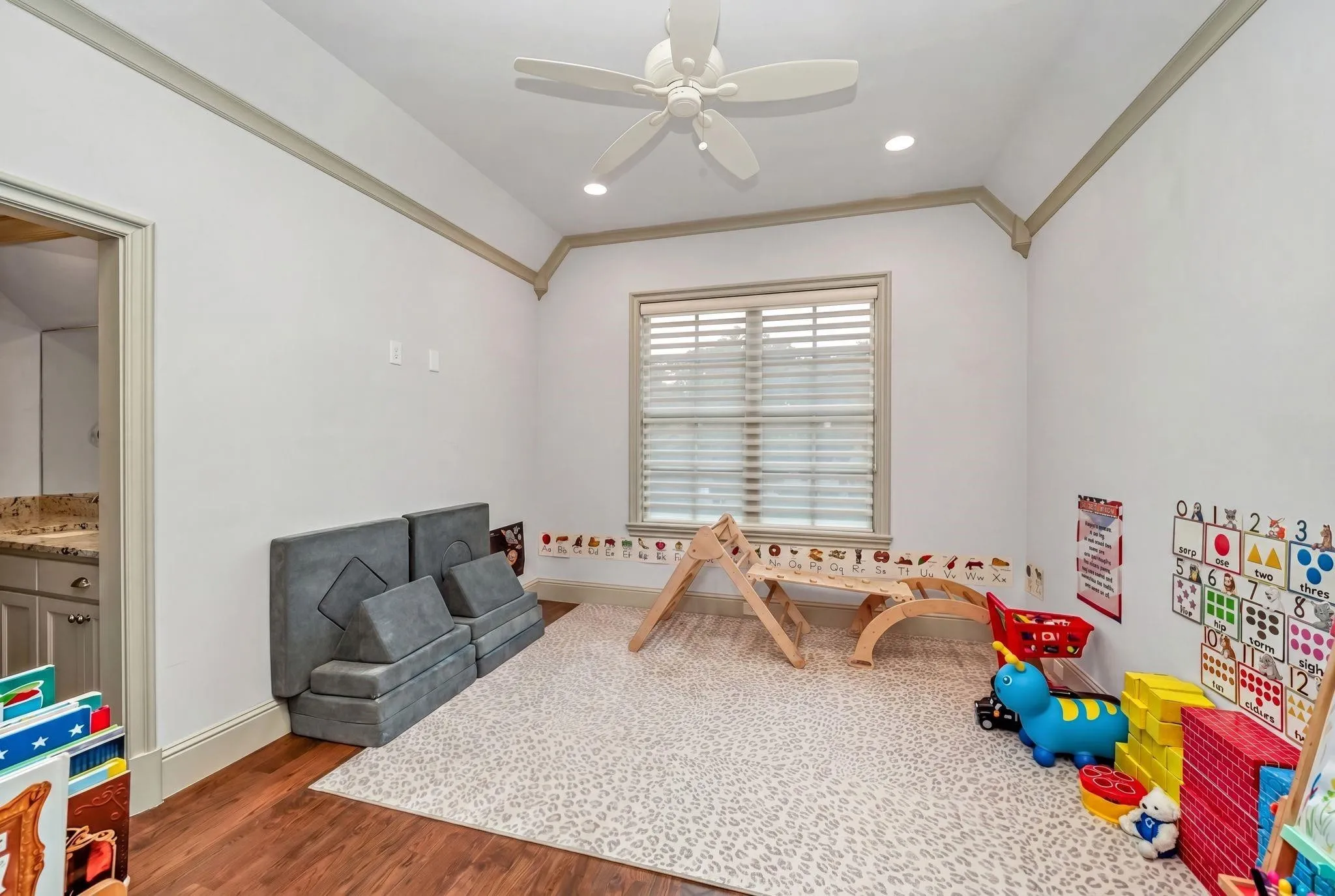 Room featuring wood-finish flooring, white walls, and a dropped ceiling with crown molding