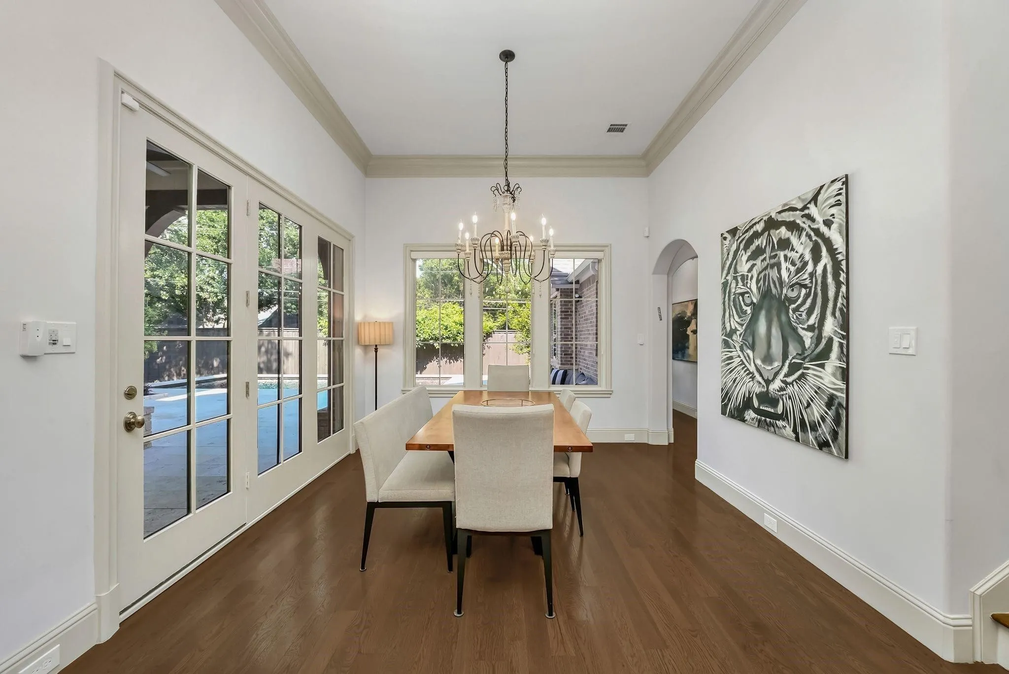 Spacious room featuring wood-finish flooring, white walls, and elegant crown molding