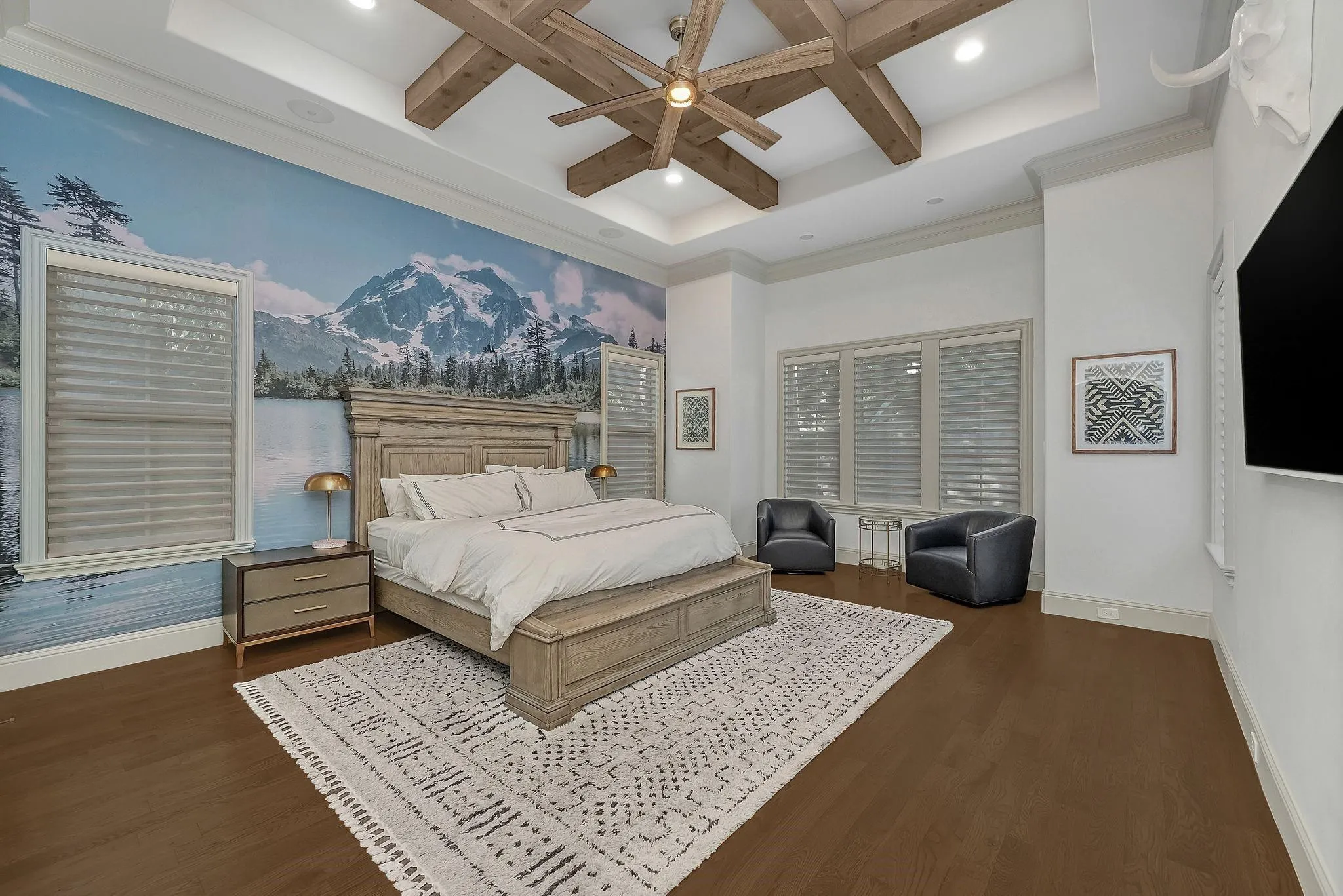 Expansive room featuring a unique wall mural, coffered ceiling with a ceiling fan, and rich wood-finish flooring