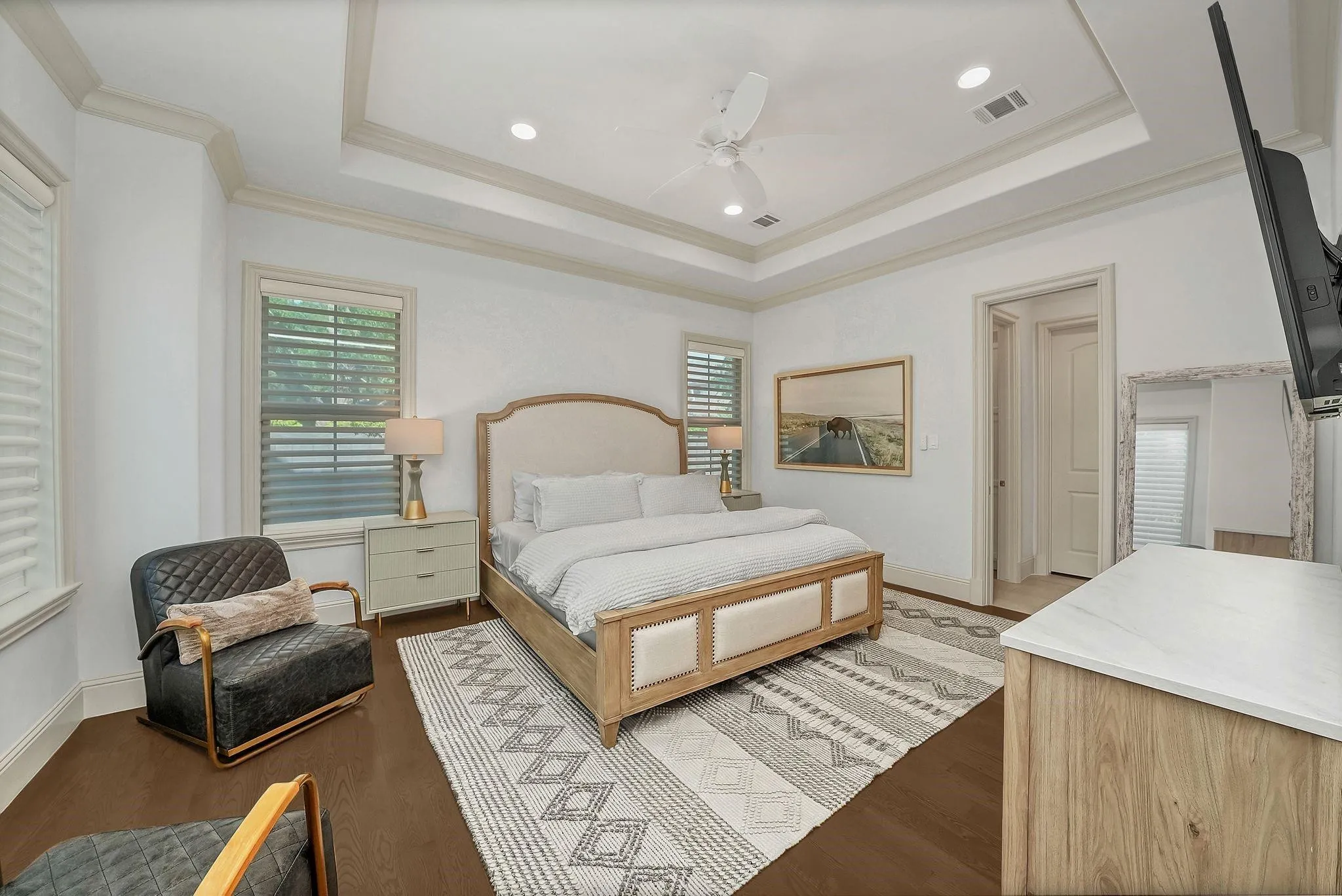 Bedroom featuring dark wood-finish flooring, a tray ceiling with recessed lighting and a ceiling fan, and multiple windows with horizontal blinds