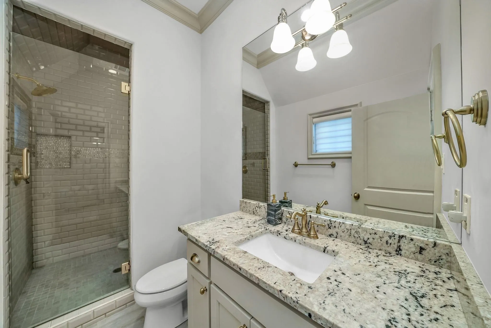 Bathroom featuring a frameless glass shower enclosure with subway tile surround, built-in shower niche, and a rain showerhead