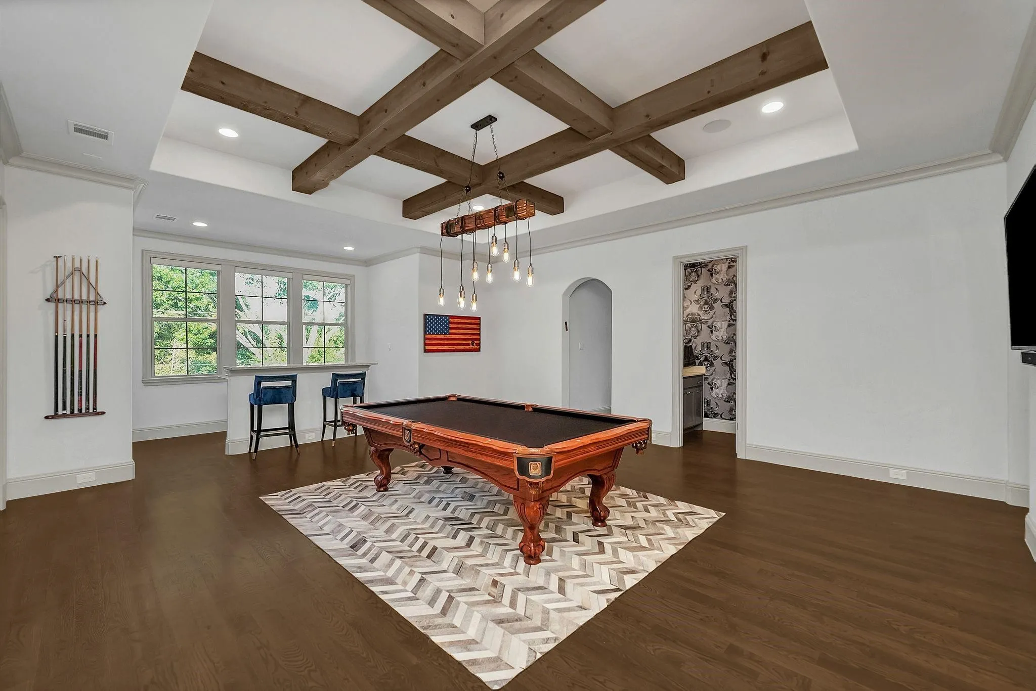 Spacious room featuring coffered ceilings with exposed wood beams, recessed lighting, and wood-finish flooring