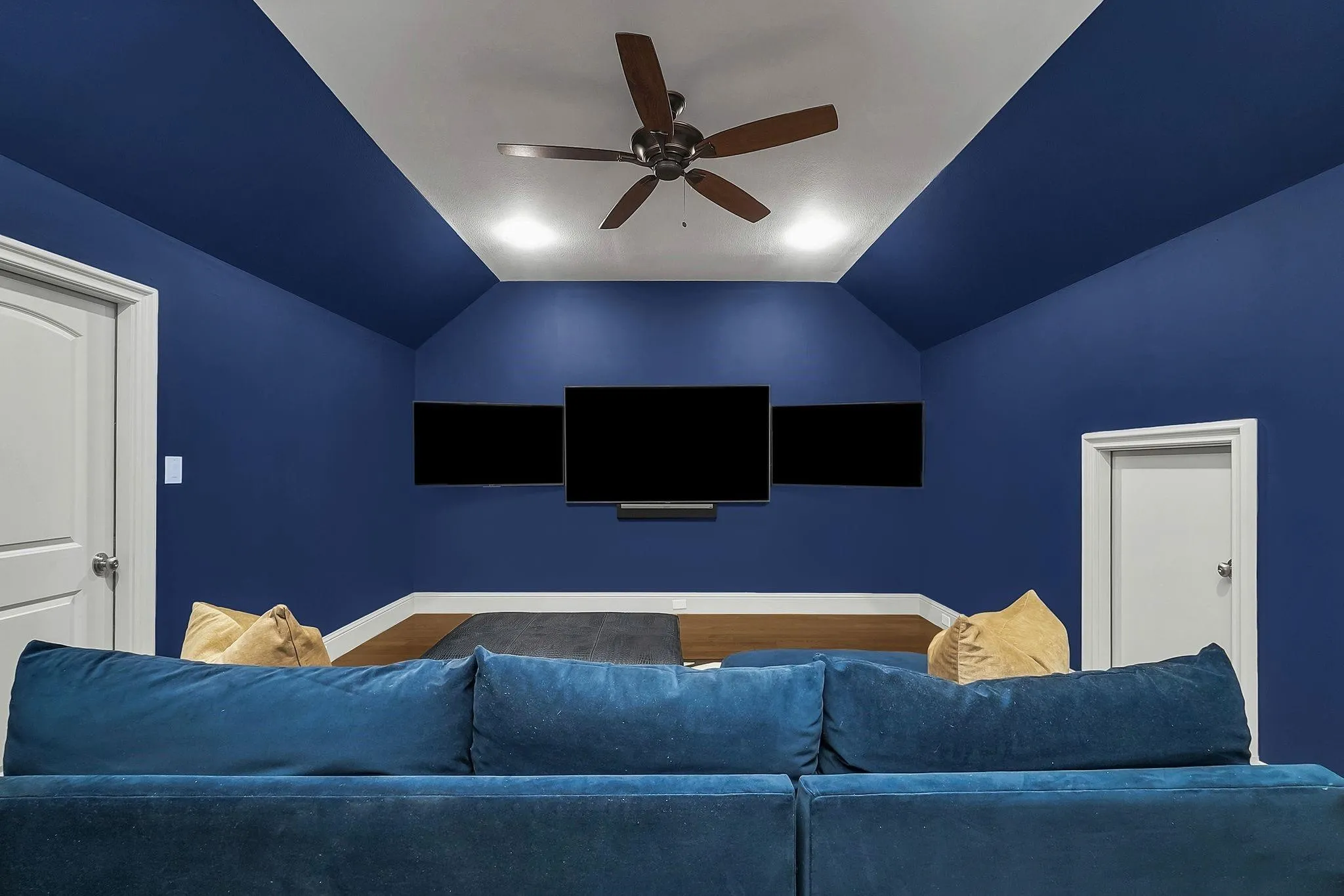 Media room with deep blue walls and a vaulted ceiling featuring recessed lighting and a ceiling fan