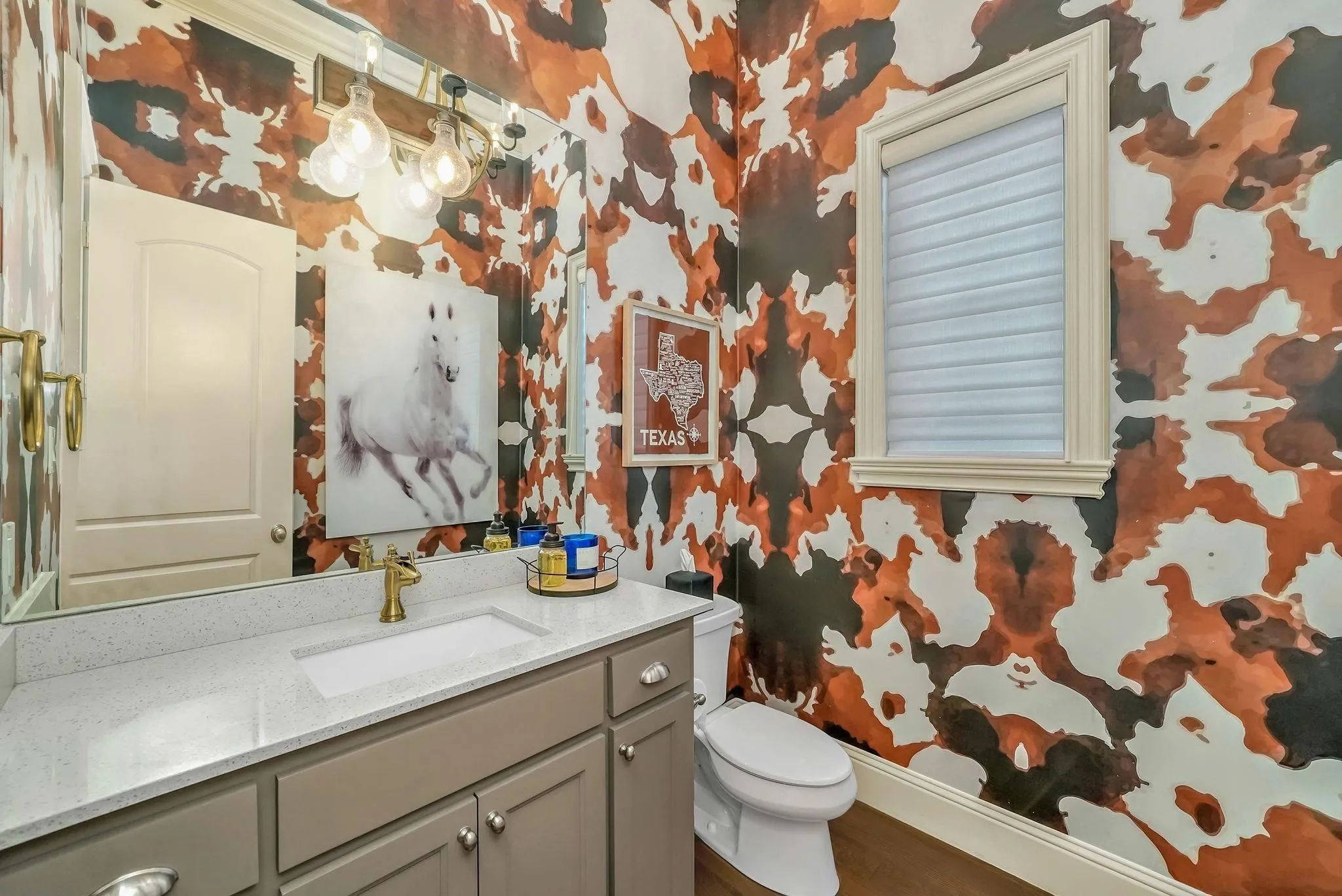 Powder room featuring bold patterned wallpaper, a single vanity with a light-toned countertop, and a rectangular undermount sink