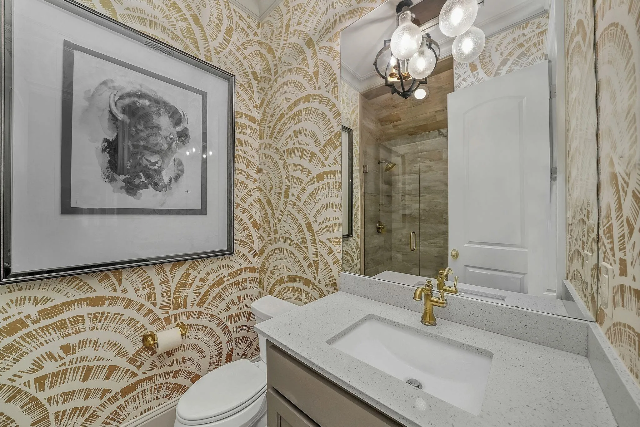 Bathroom vanity featuring a light-toned countertop with integrated sink, brass-finish faucet, and a large mirror