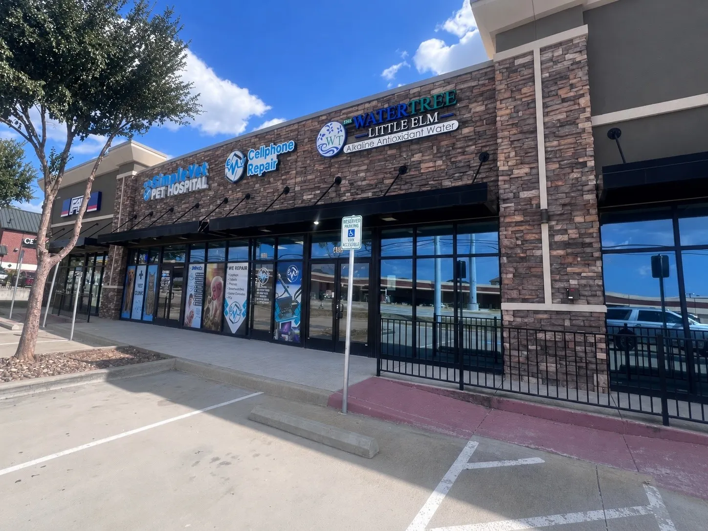 Storefront with a stone facade, prominent signage, expansive display windows, and black awnings