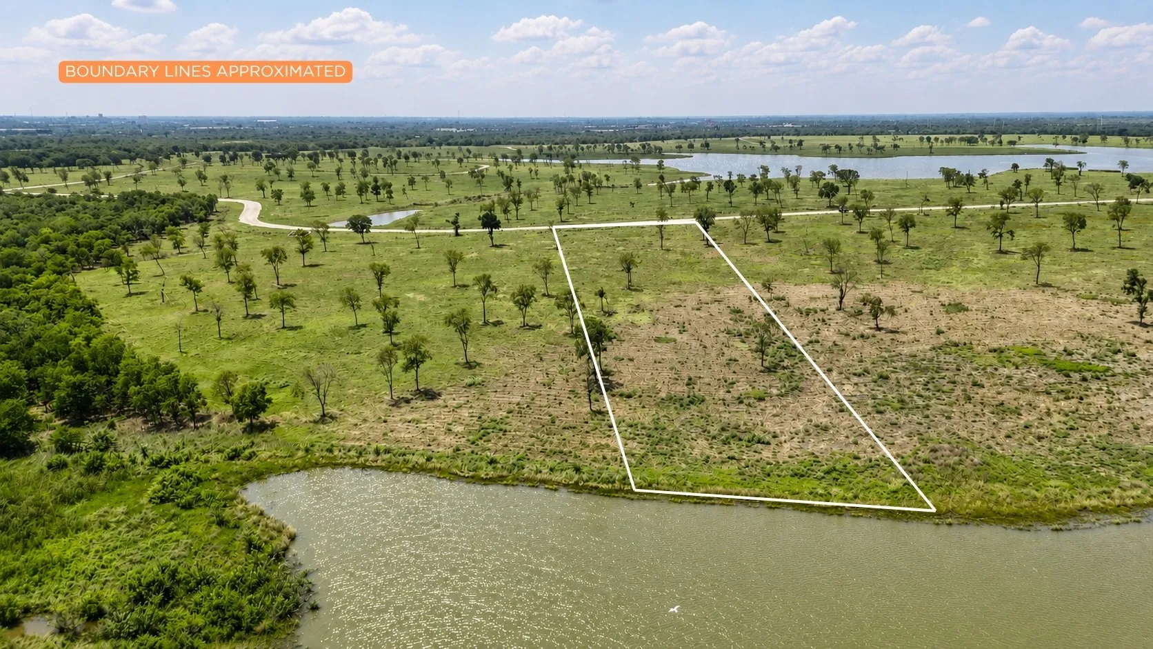Elevated drone perspective highlighting the homesite's waterfront setting and open build area.