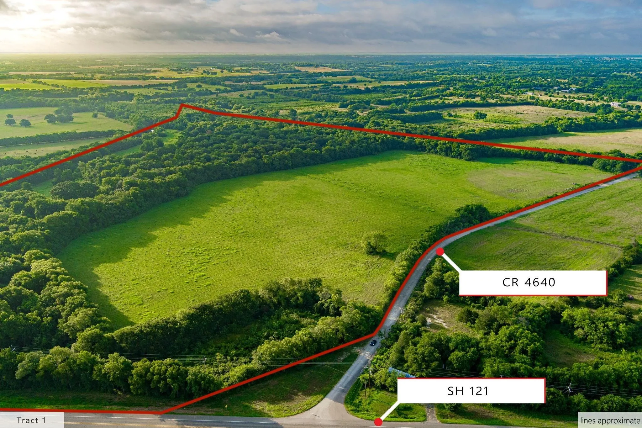 Expansive land parcel featuring open green fields and mature tree lines