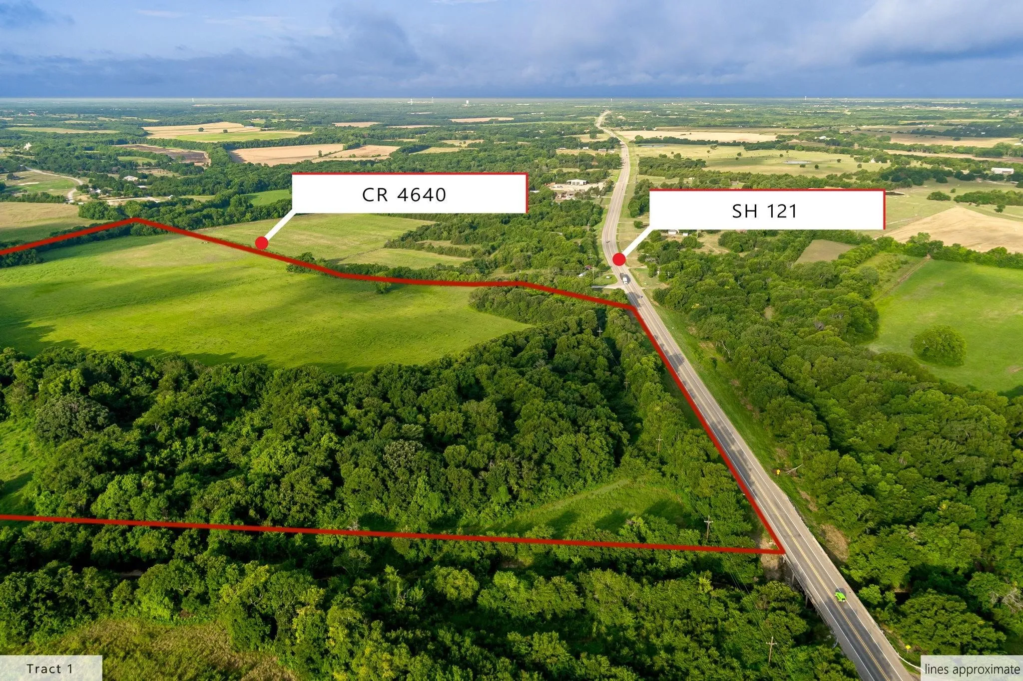 Aerial view of expansive land featuring green fields and abundant tree coverage