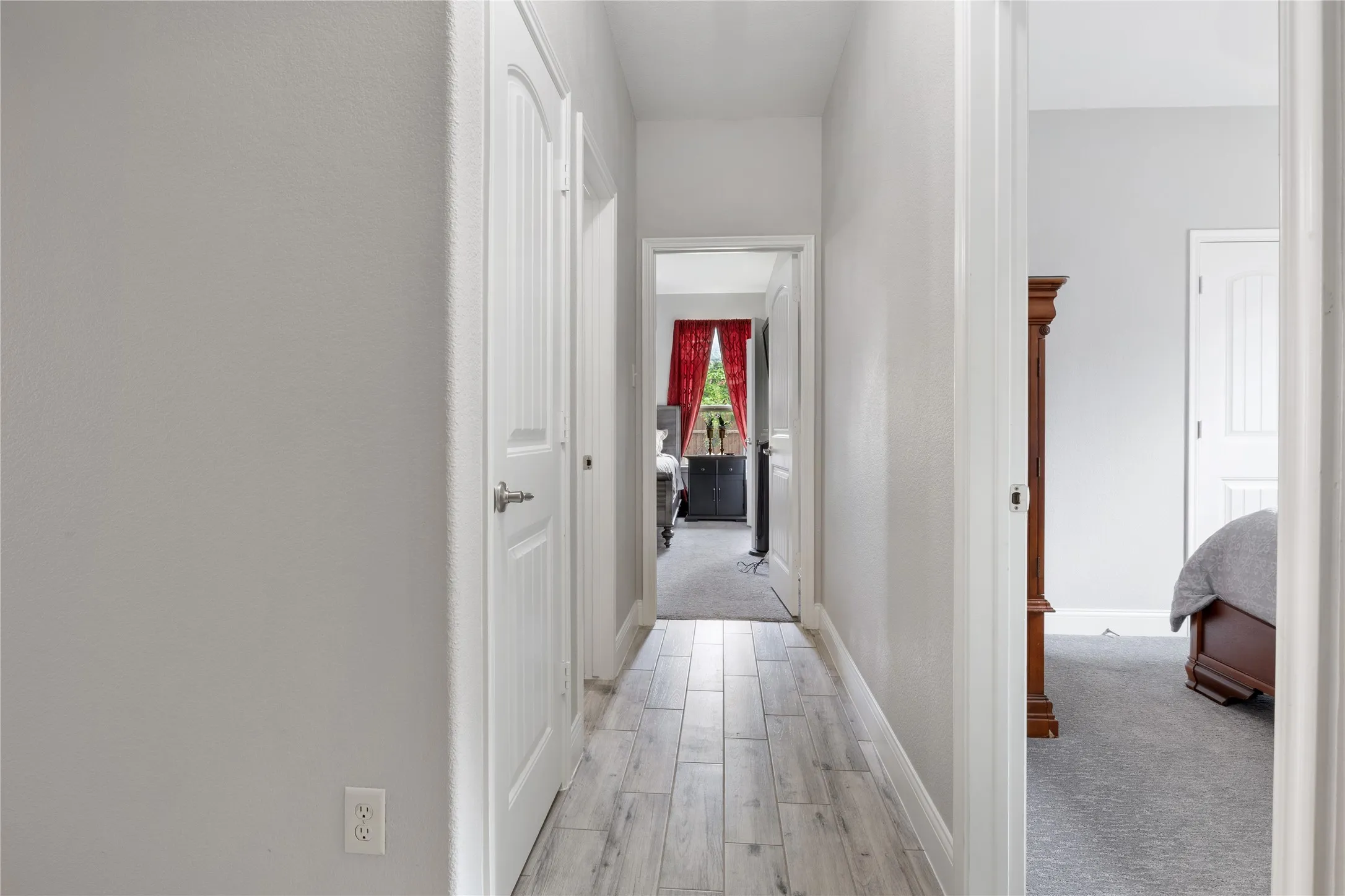 Hallway with wood-finish flooring, white paneled doors, and light gray wall paint