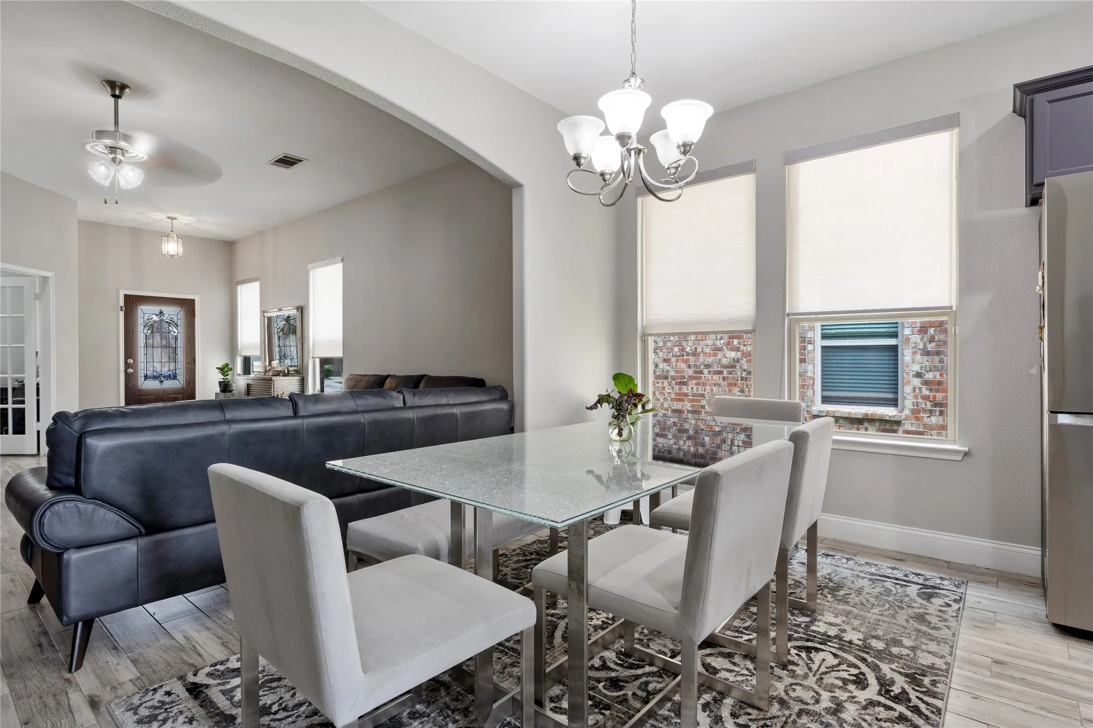 Dining area featuring a contemporary chandelier, two windows with roller shades, and wood-finish flooring