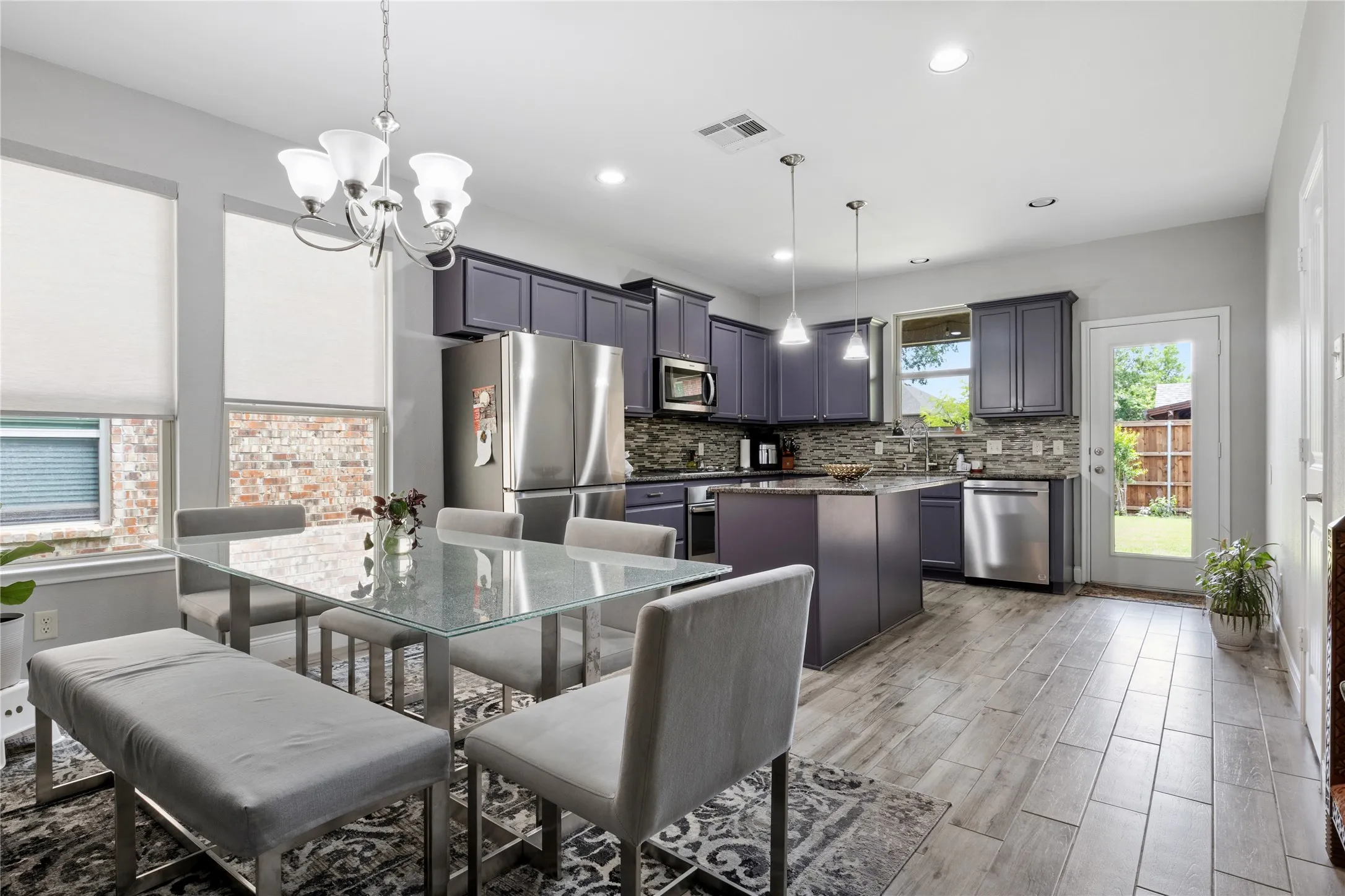 Open-concept kitchen and dining area featuring wood-finish flooring, recessed lighting, and a glass-paneled back door