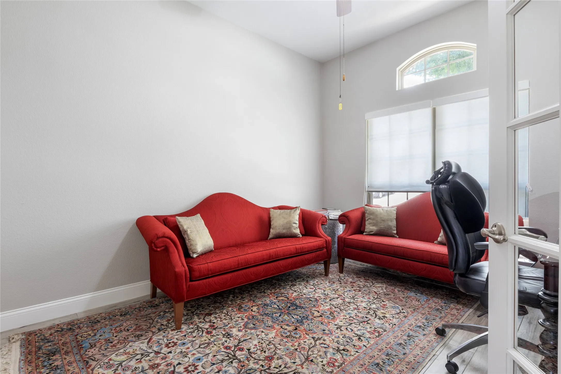 Vaulted ceiling space featuring an arched transom window and two large windows with blinds