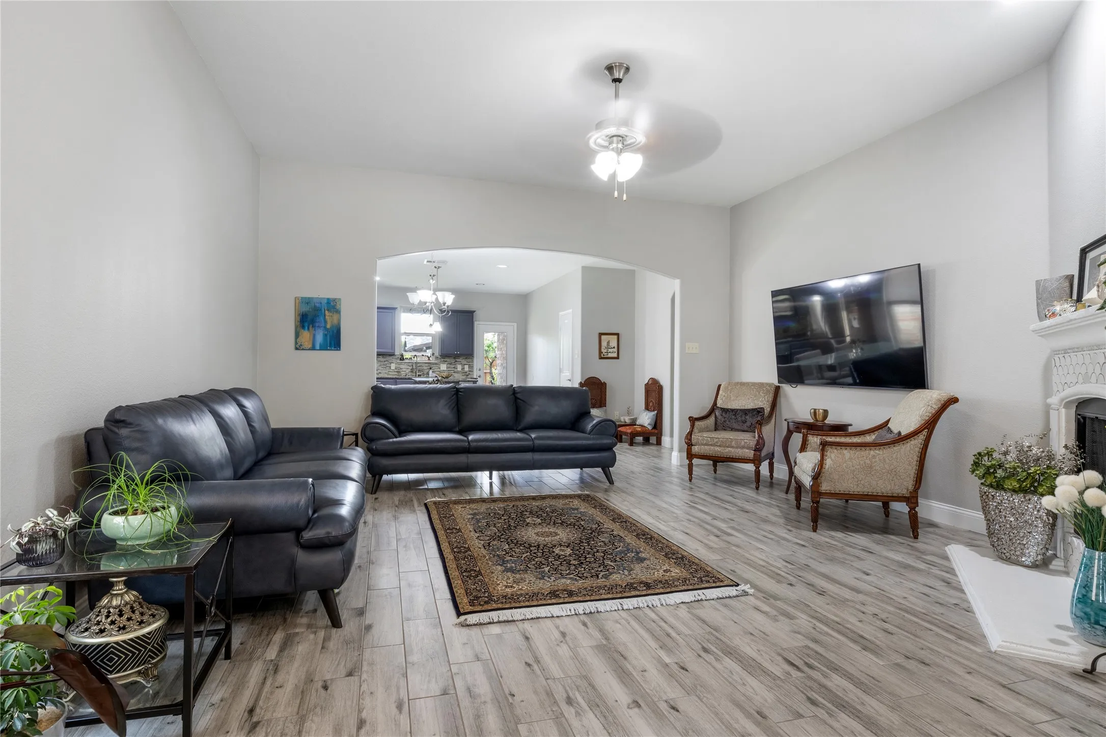 Spacious living area featuring wood-finish flooring, a decorative fireplace, and an arched entryway