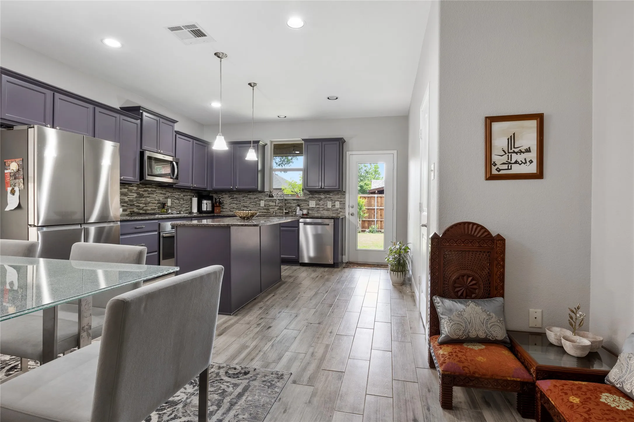 Open-concept kitchen featuring wood-finish flooring, recessed lighting, and a glass-paneled door