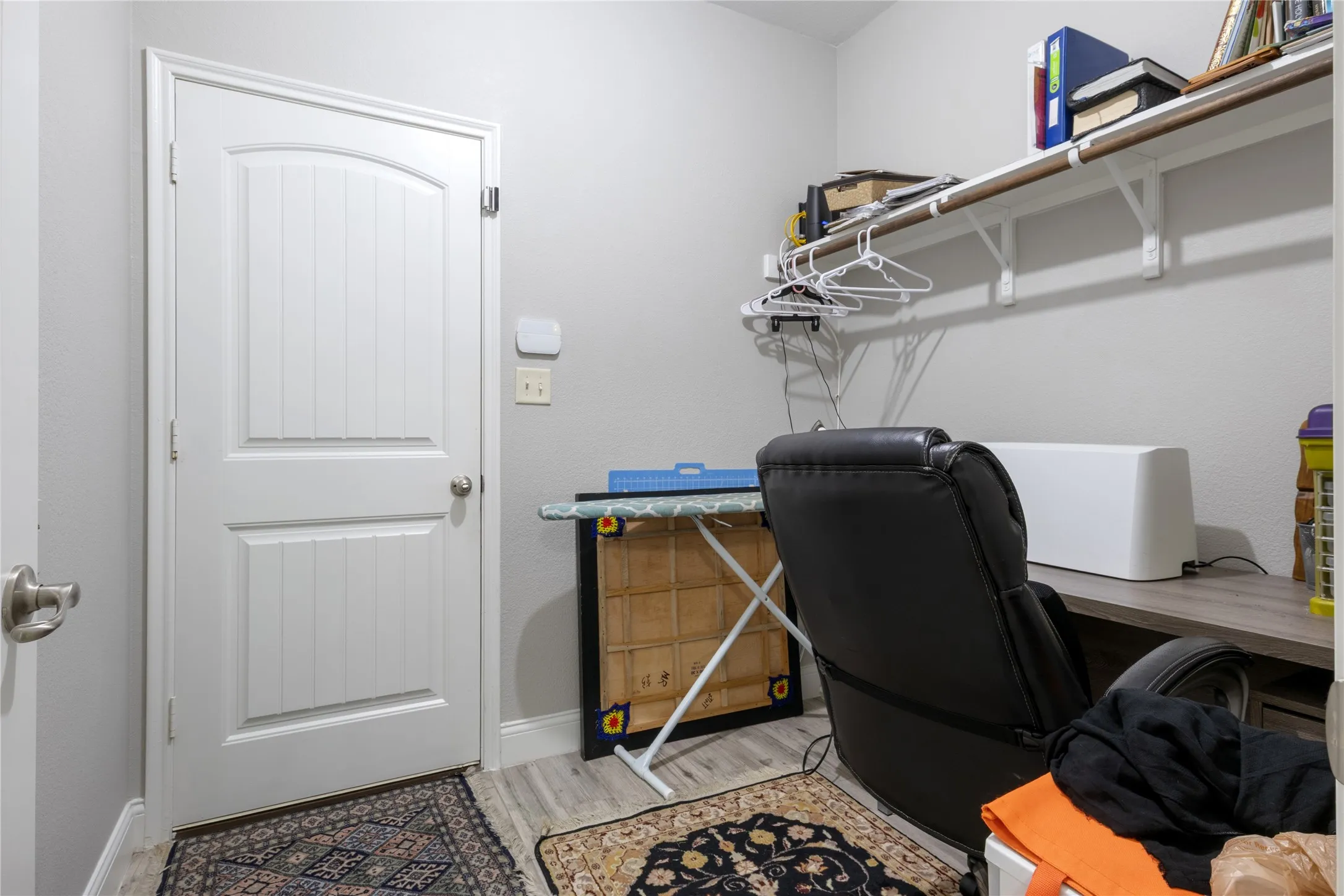 Laundry room featuring a paneled door, wood-finish flooring, and a built-in shelf with hanging rod