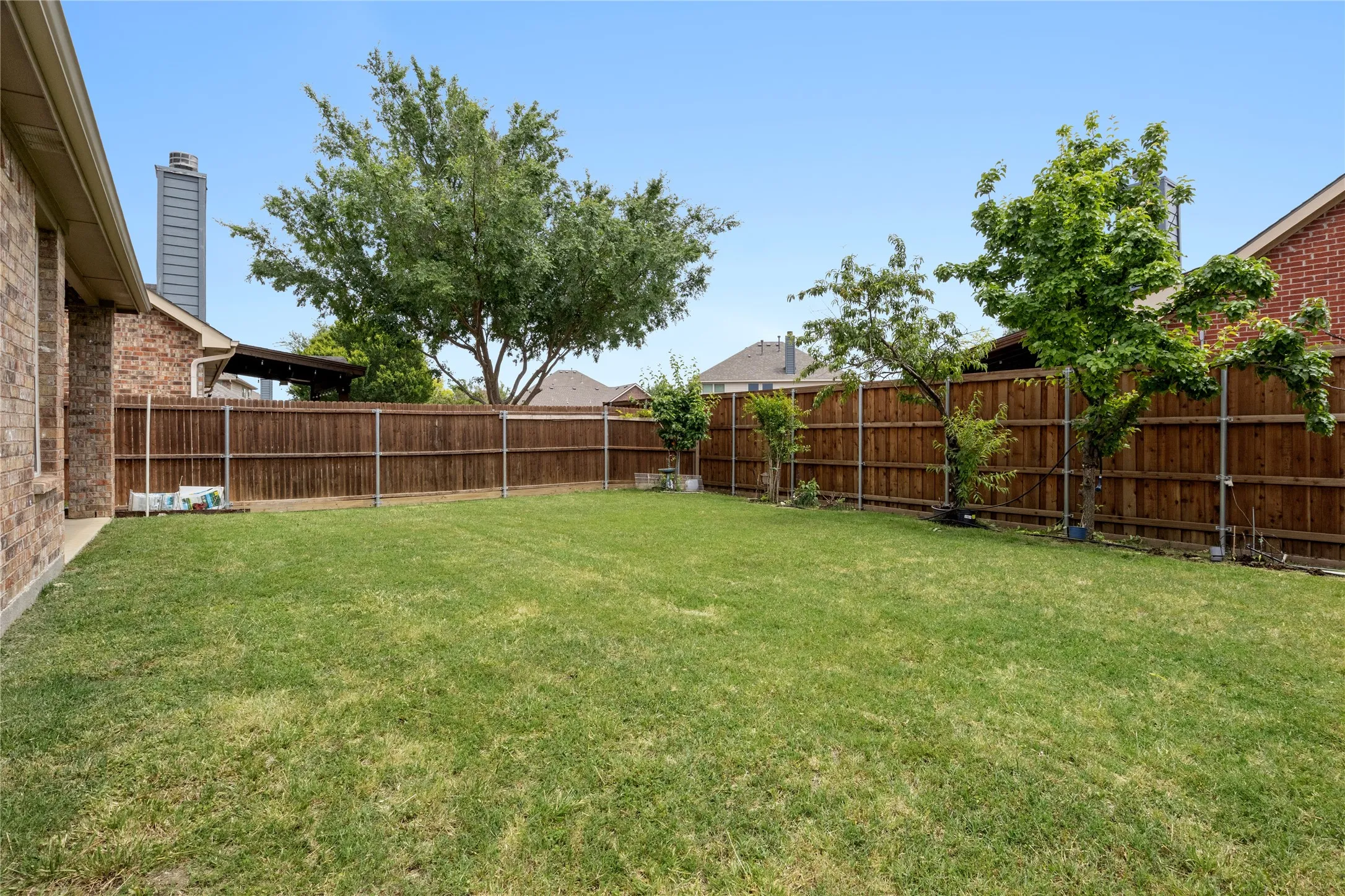 Expansive backyard featuring a manicured lawn, established privacy fencing, and mature trees