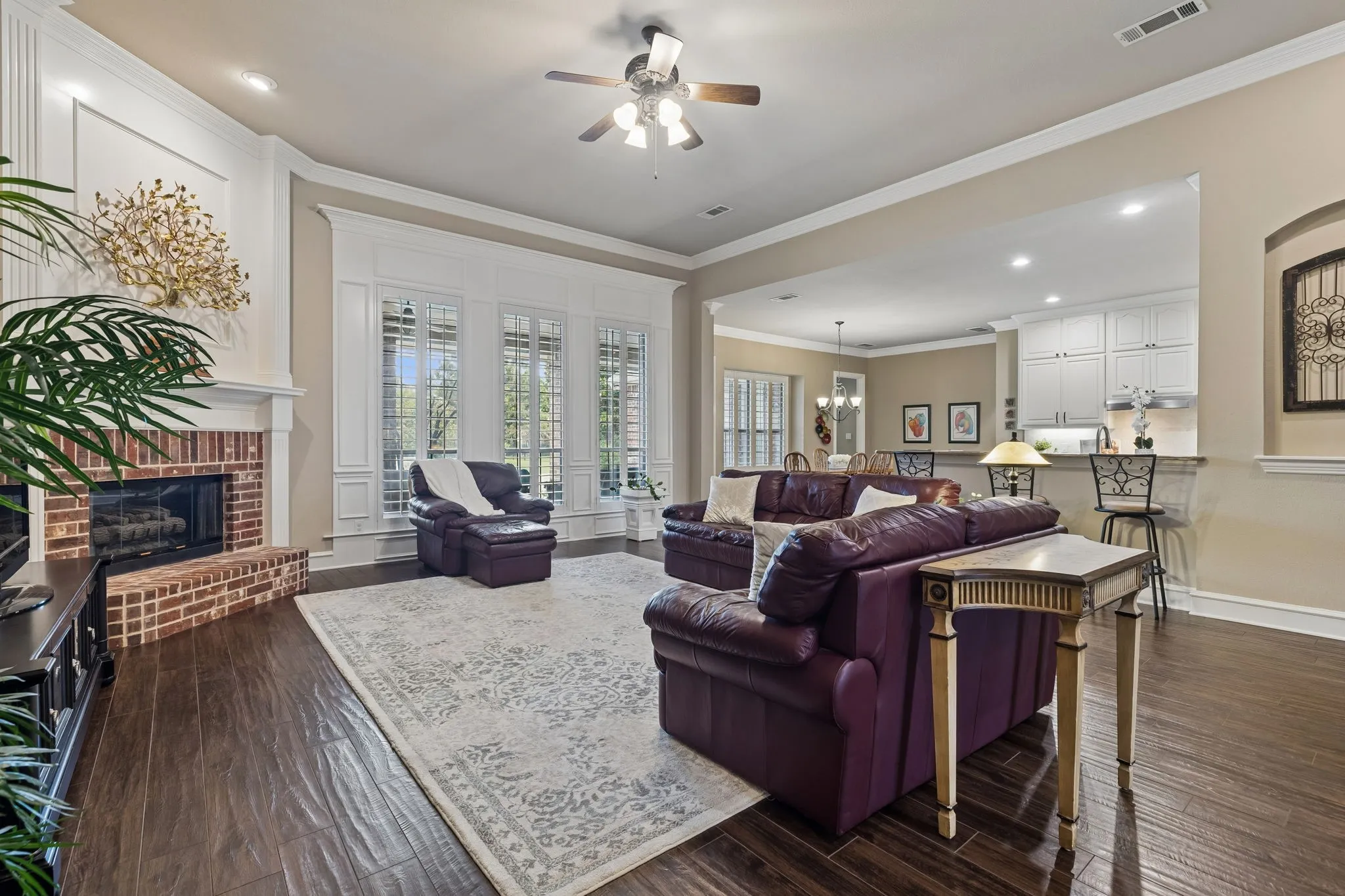The main living area boasts 12 foot ceilings, crown molding, plantation shutters trimmed with beautiful crown molding, ceiling fan, recessed lighting, wood like tile floors and a stunning gas fireplace with brick and wood trim.