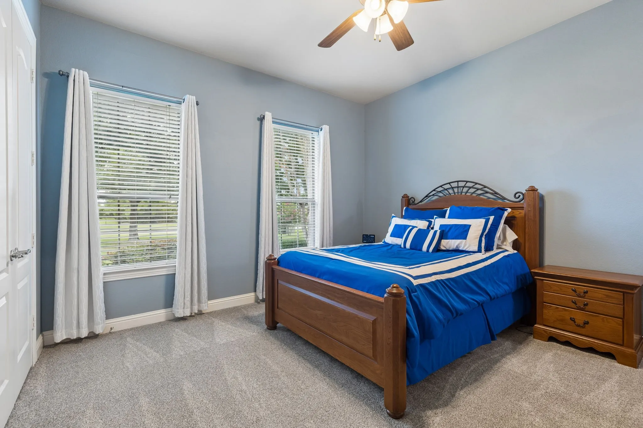 Down the hall from the primary bedroom is another spacious secondary bedroom, featuring views of the front yard, ceiling fan and a spacious closet.