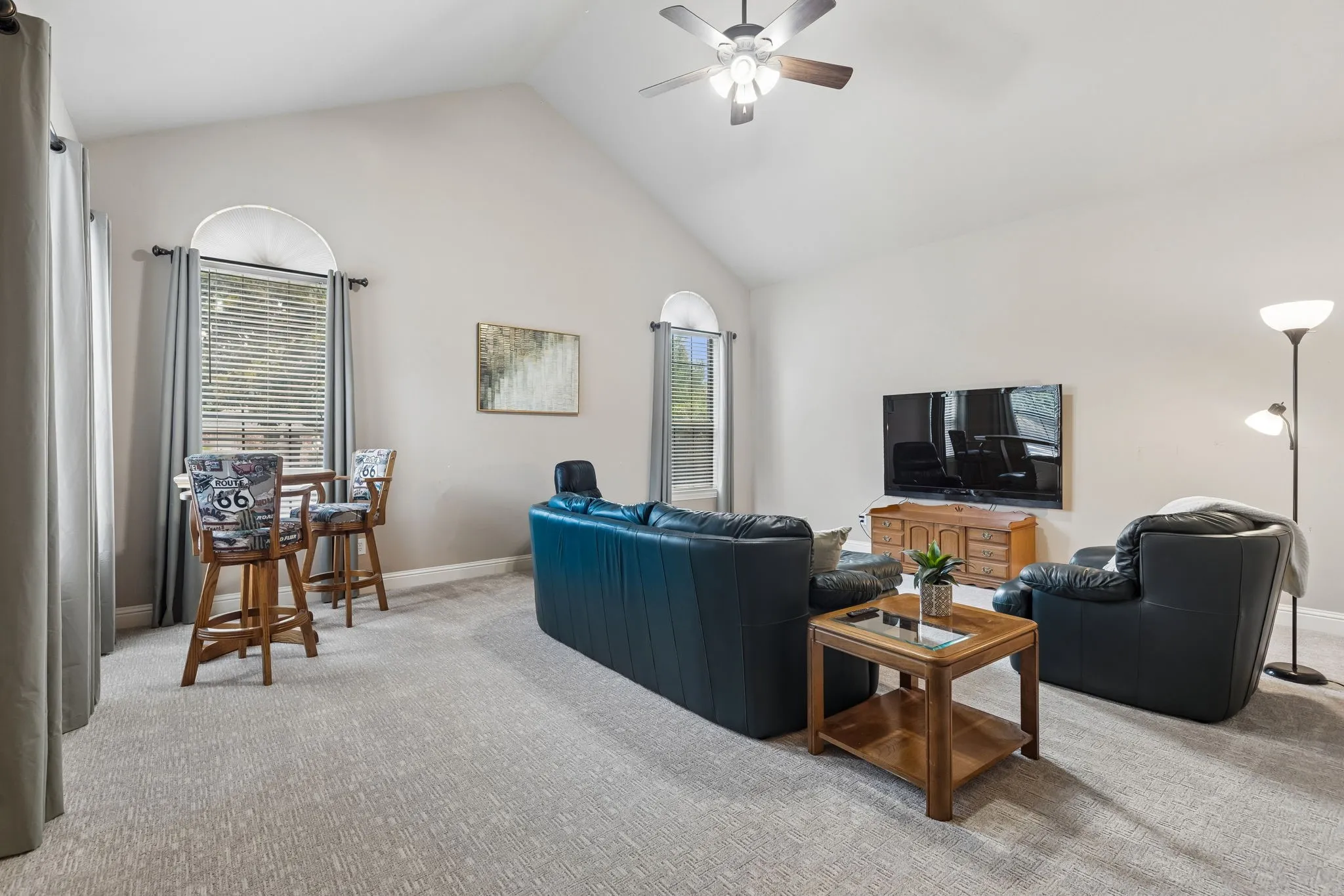 Welcome to the large game room! This room features fresh carpet, soaring vaulted ceilings, ceiling fan, large windows with views of the outside and a door leading to the pool and outdoor living space.