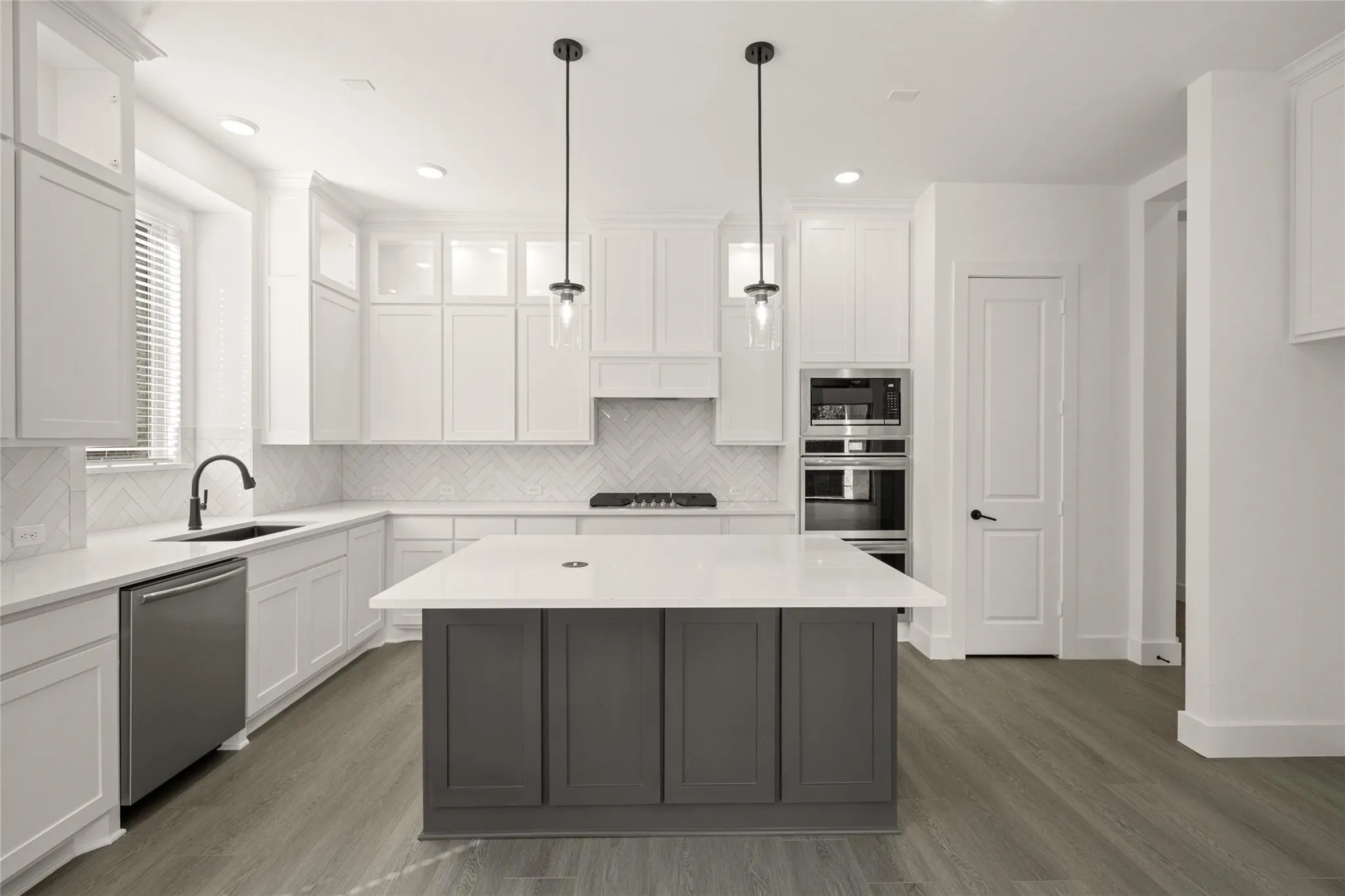 Dual tone kitchen featuring two tone color scheme, dark wood finished floors, stainless steel appliances, light stone countertops, and a center island