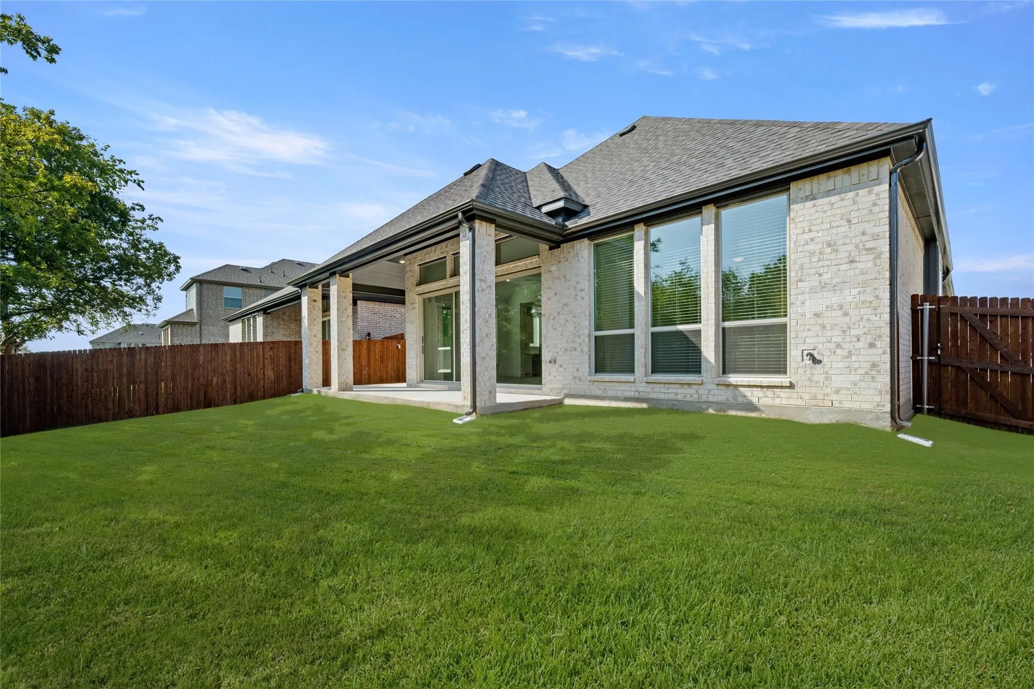 Back of house with a patio area, brick siding, a fenced backyard, and roof with shingles