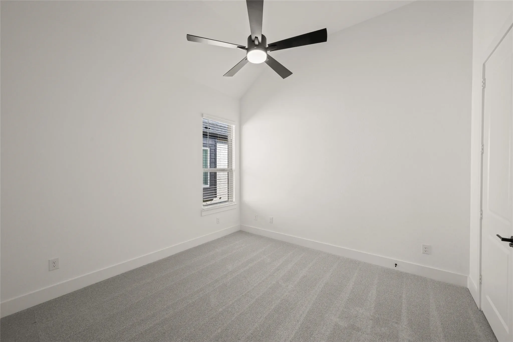 Carpeted empty room with lofted ceiling and a ceiling fan
