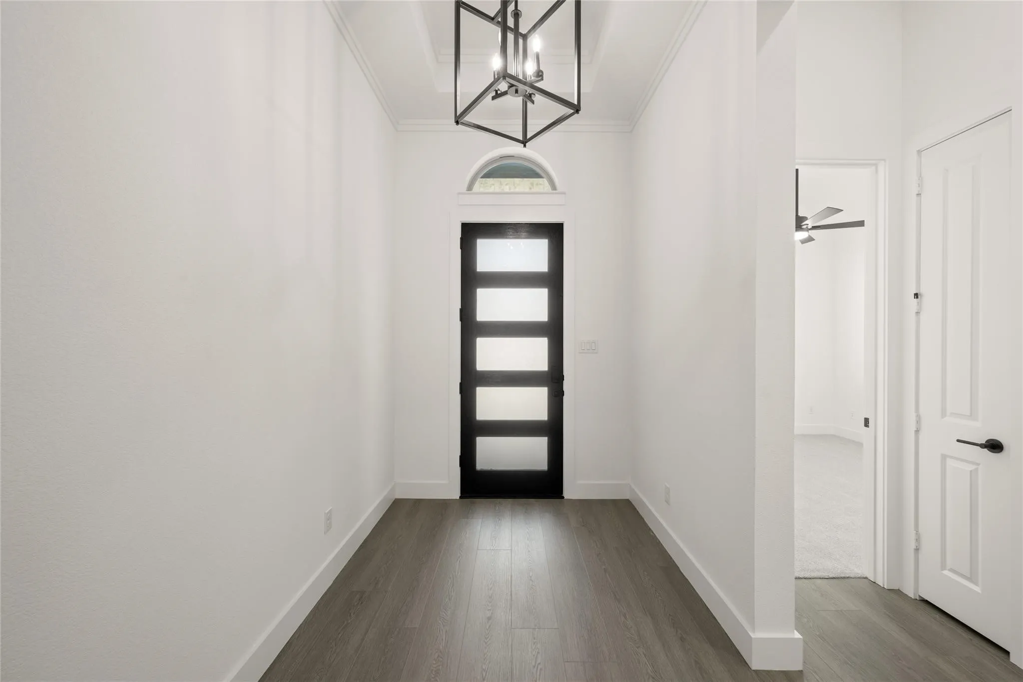 Entrance foyer featuring dark wood finished floors, a chandelier, crown molding, and ceiling fan