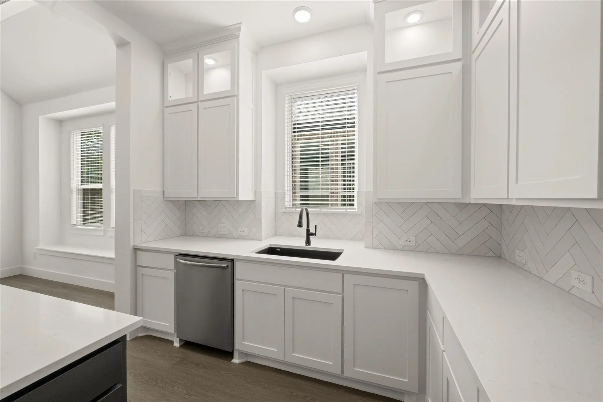 Kitchen featuring white cabinets, dark wood finished floors, glass fronted cabinets, stainless steel dishwasher, and recessed lighting