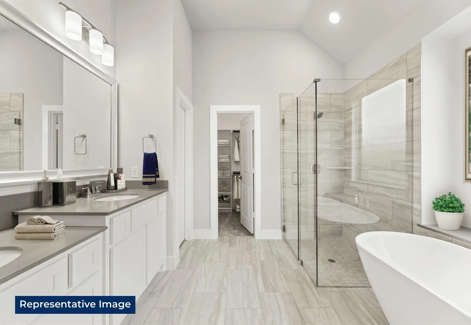 Bathroom with double vanity, a stall shower, a freestanding tub, vaulted ceiling, and a spacious closet