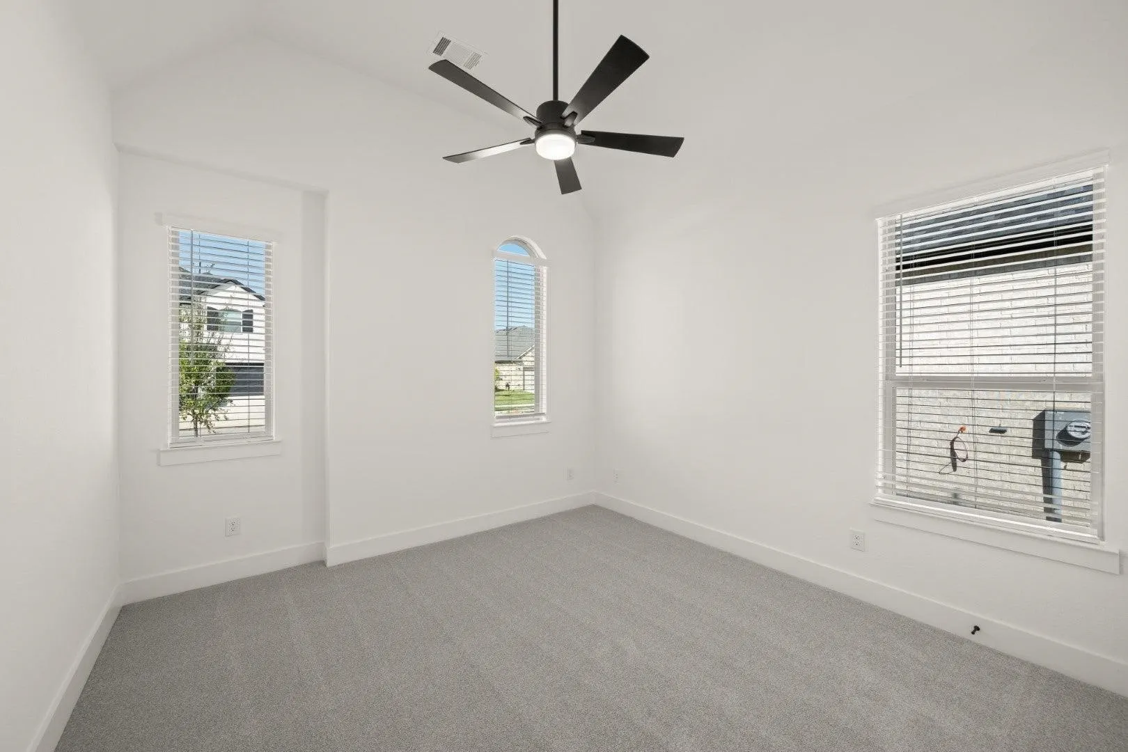 Empty room with dark carpet, lofted ceiling, and a ceiling fan