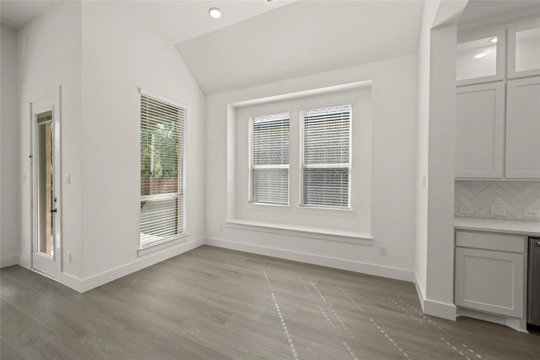 Unfurnished dining area featuring vaulted ceiling, dark wood-style flooring, and recessed lighting