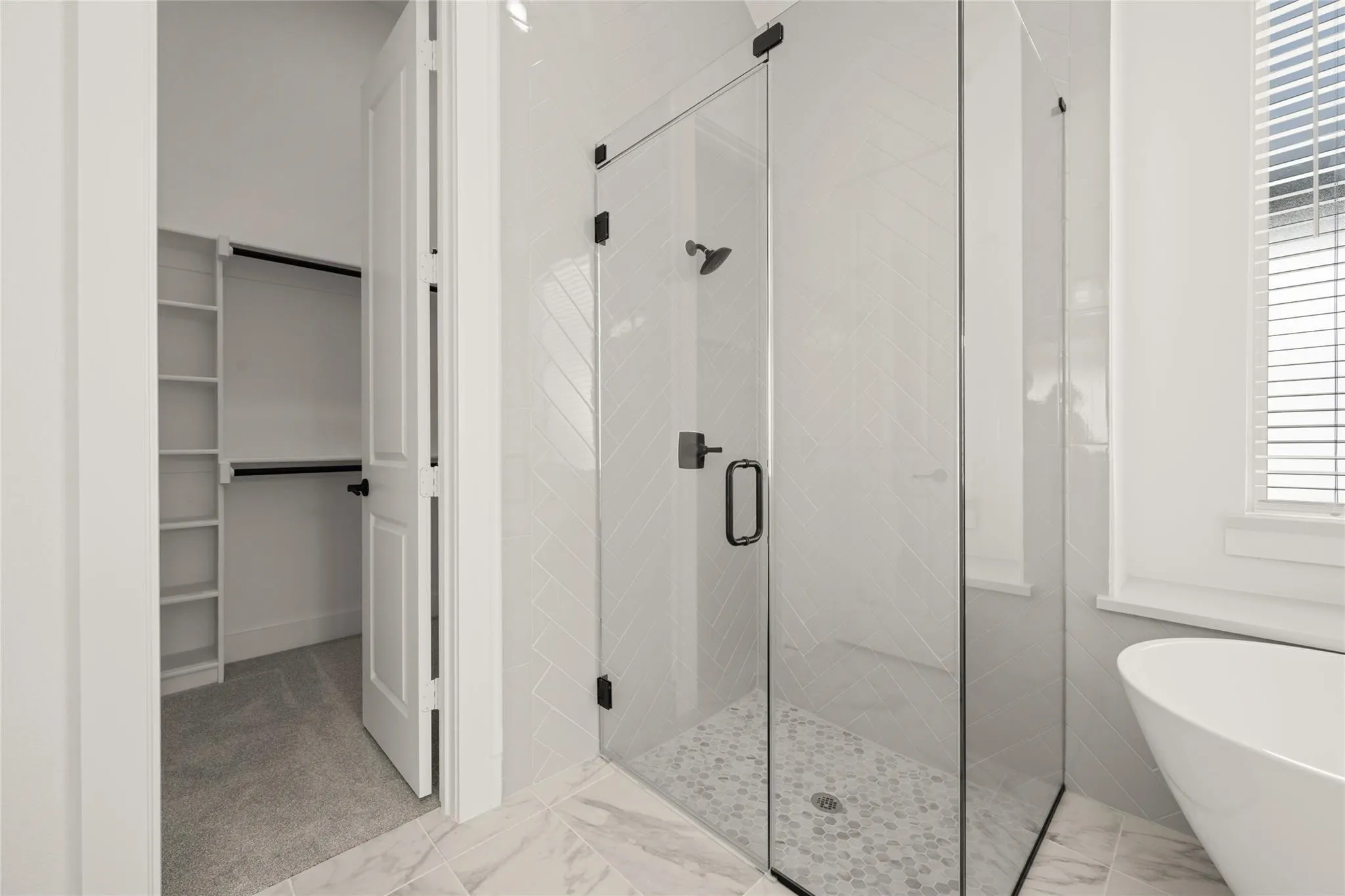 Full bathroom featuring a walk in closet, a shower stall, a soaking tub, and light marble finish flooring