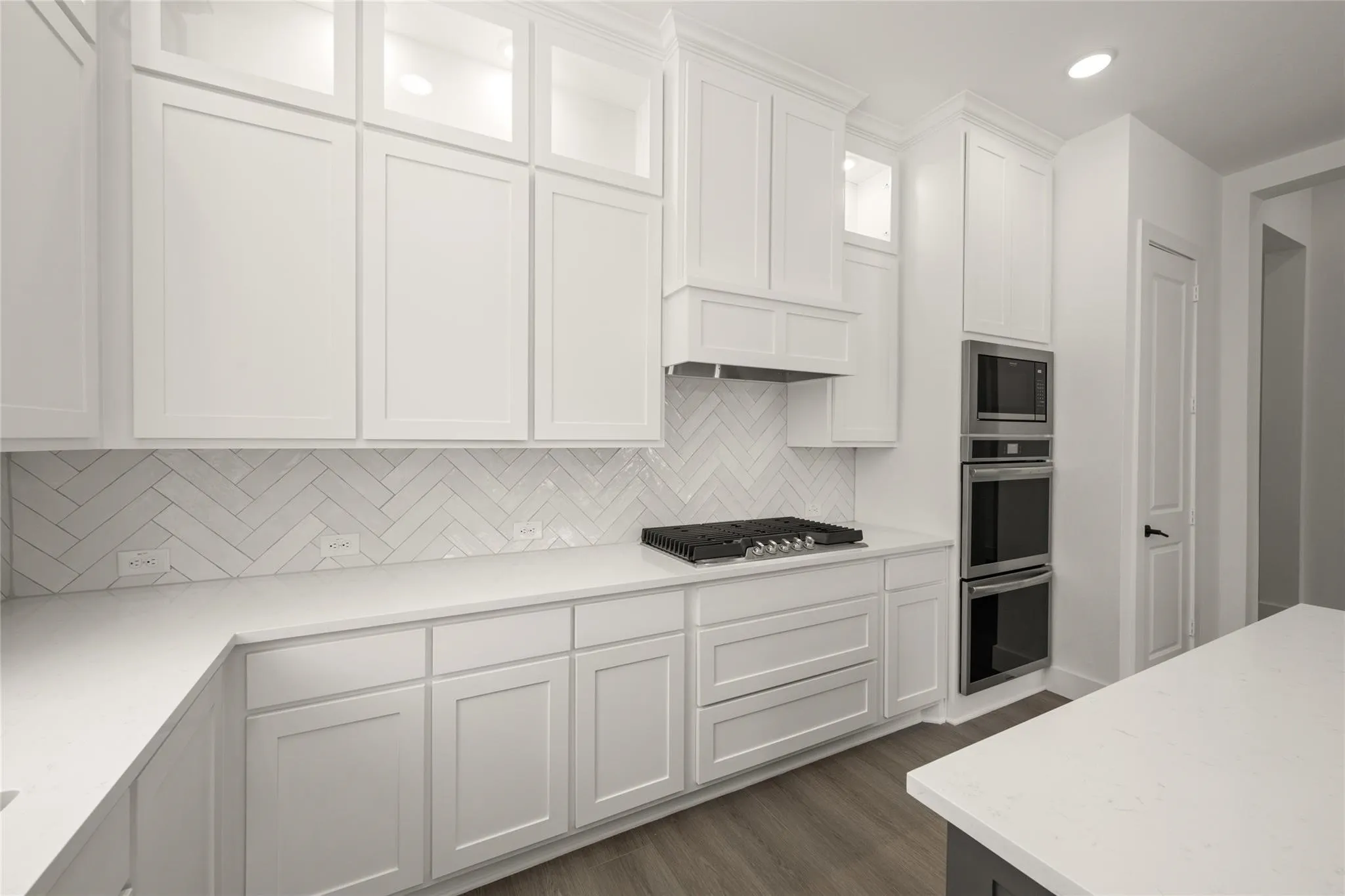 Kitchen featuring white cabinets, stainless steel appliances, dark wood-style flooring, light stone counters, and recessed lighting