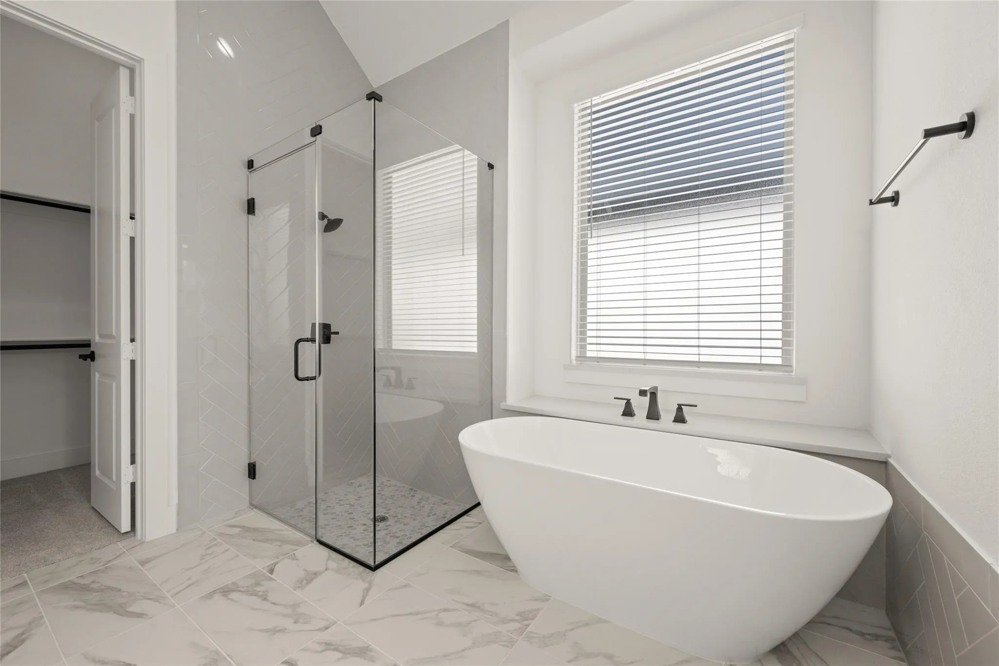 Full bath featuring a stall shower, a soaking tub, light marble finish floors, and a wainscoted wall