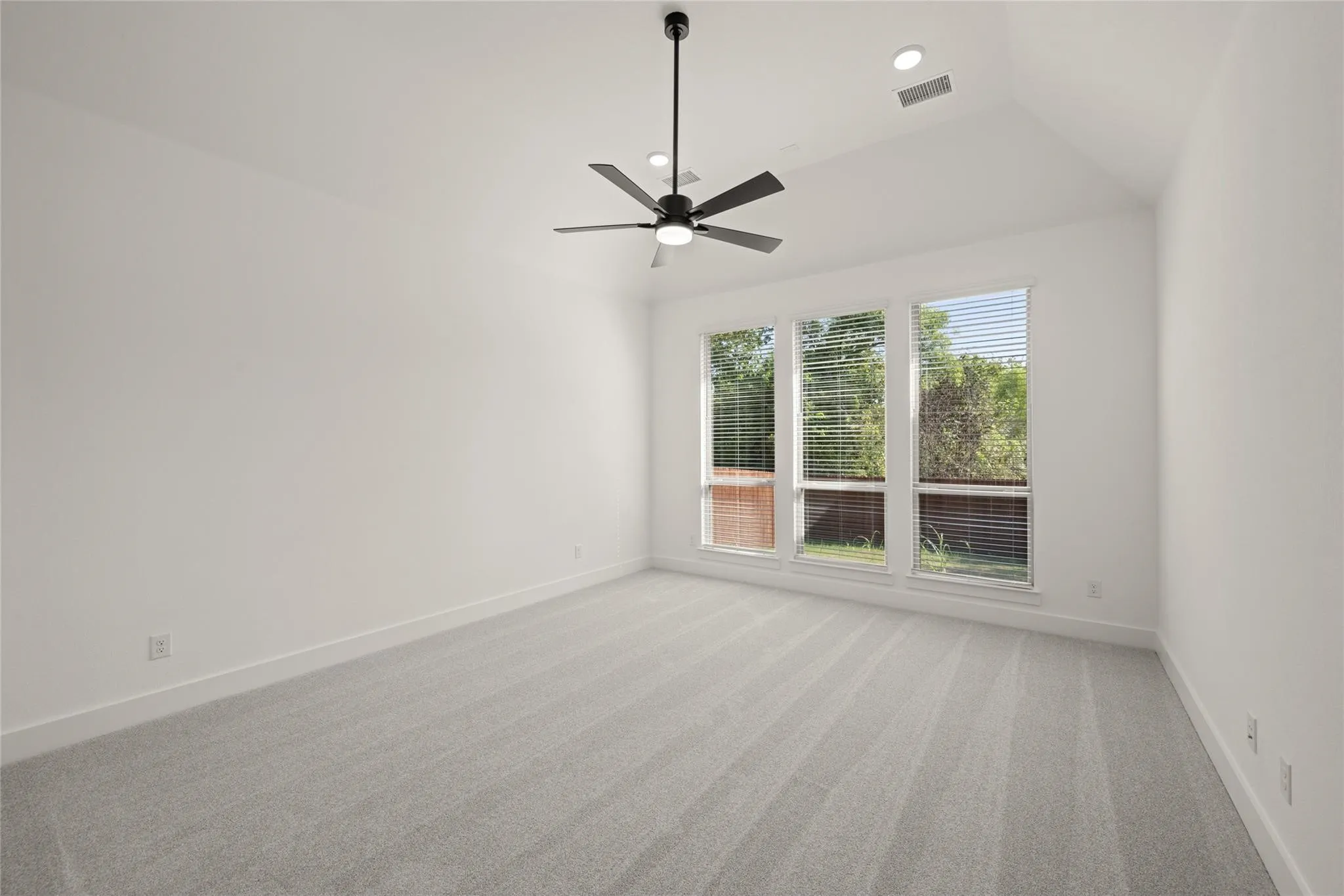 Empty room featuring light carpet, a ceiling fan, and lofted ceiling