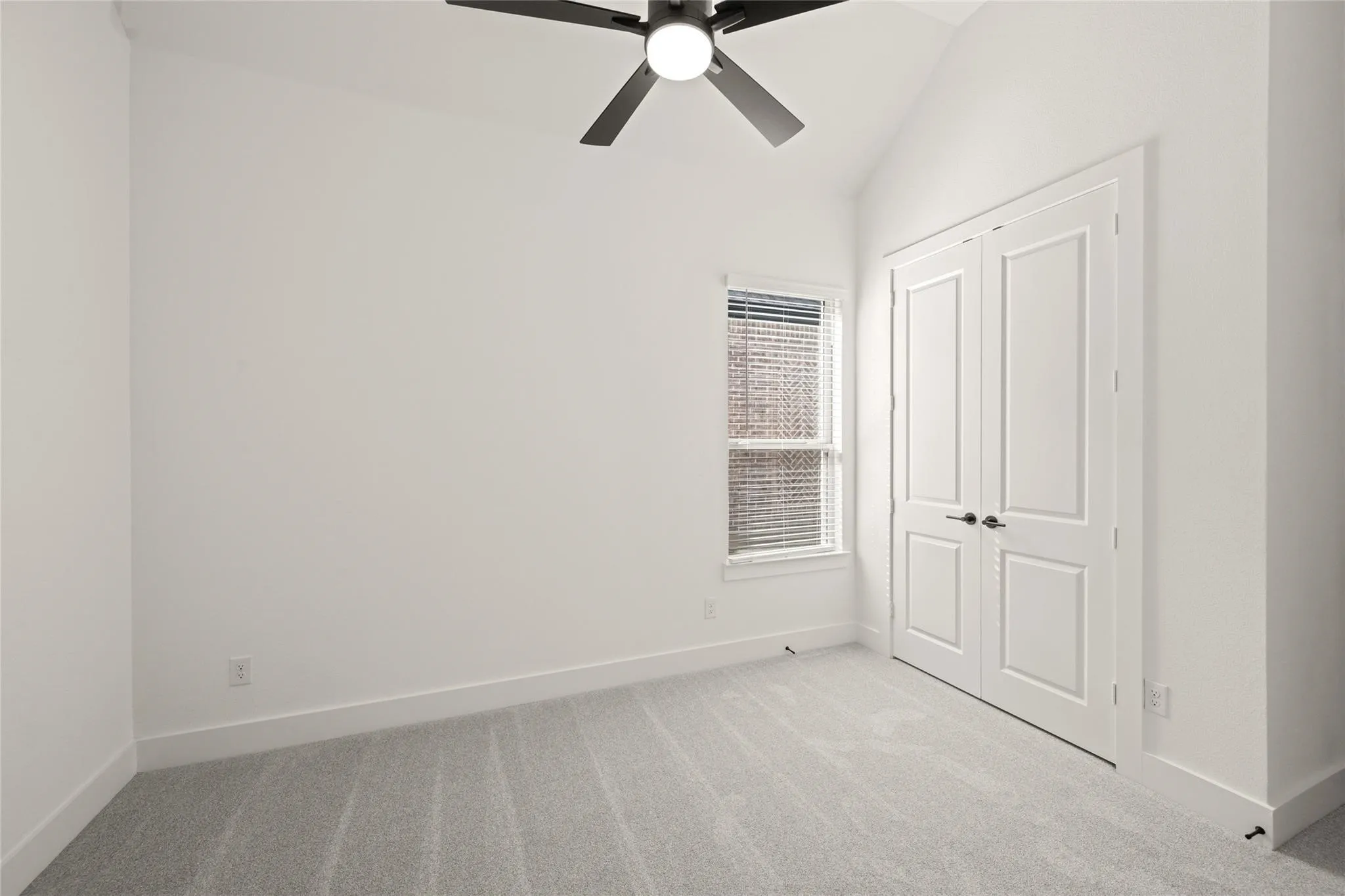 Unfurnished bedroom with light carpet, vaulted ceiling, a ceiling fan, and a closet