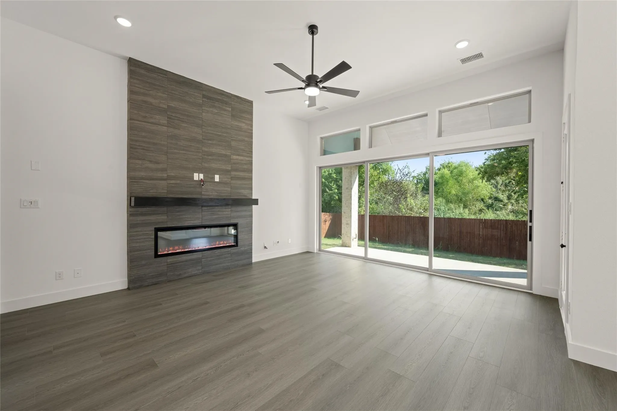 Unfurnished living room with ceiling fan, a large fireplace, dark wood finished floors, and recessed lighting