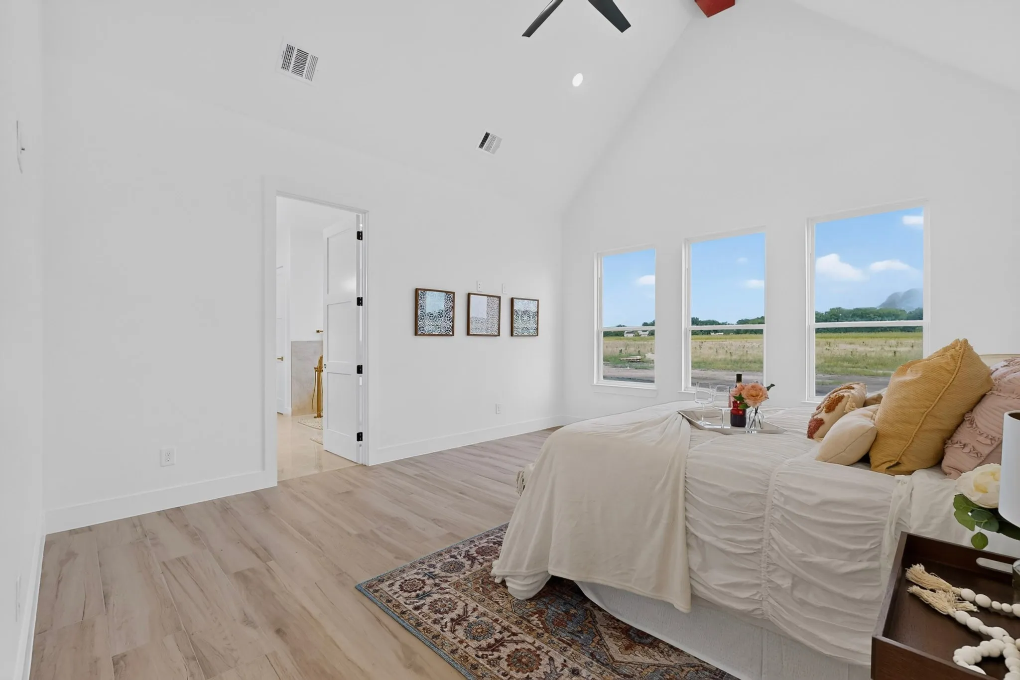 Room featuring wood-finish flooring, white walls, and a vaulted ceiling with a ceiling fan